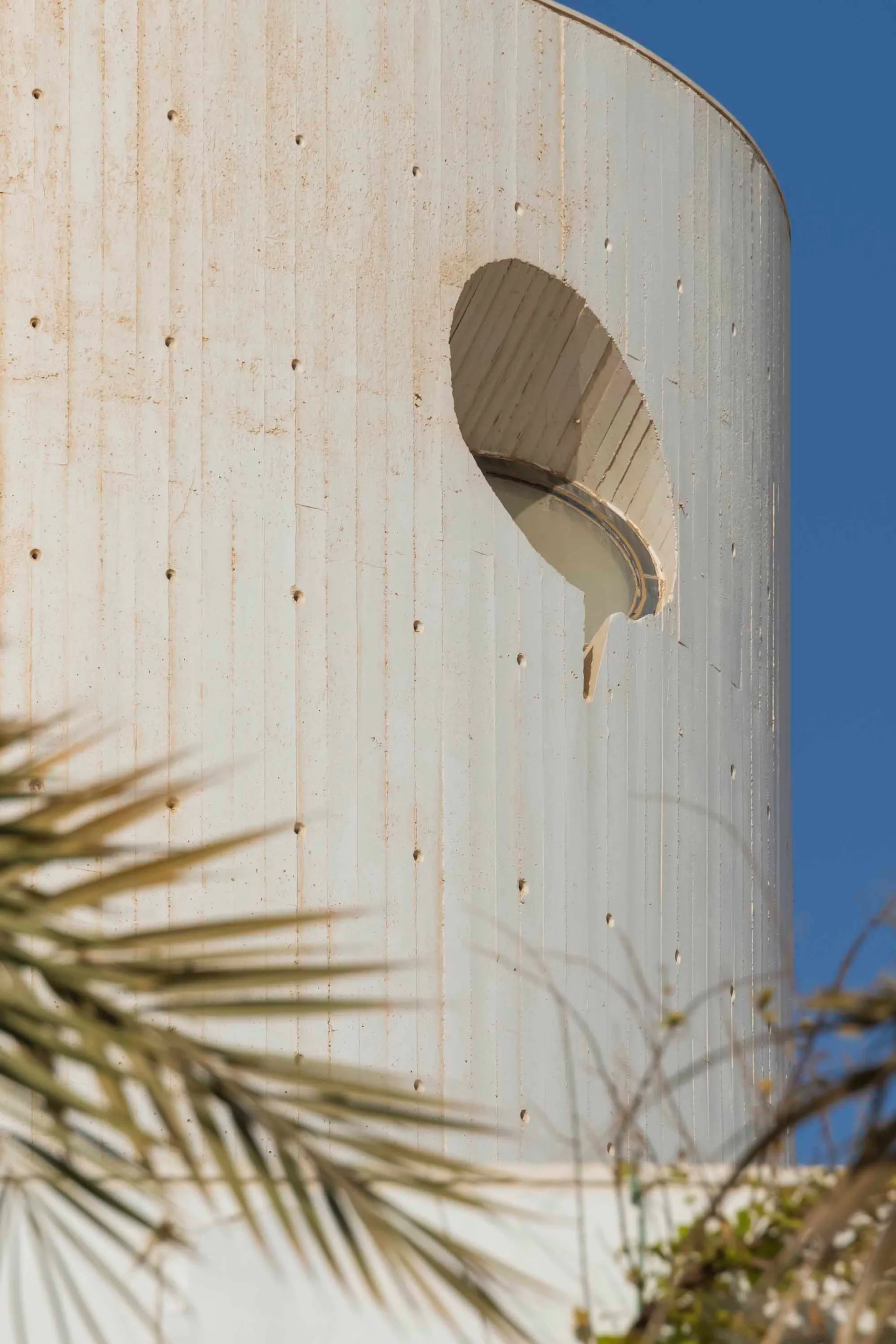 Close-up of a modern building exterior with a circular window and bullet holes.