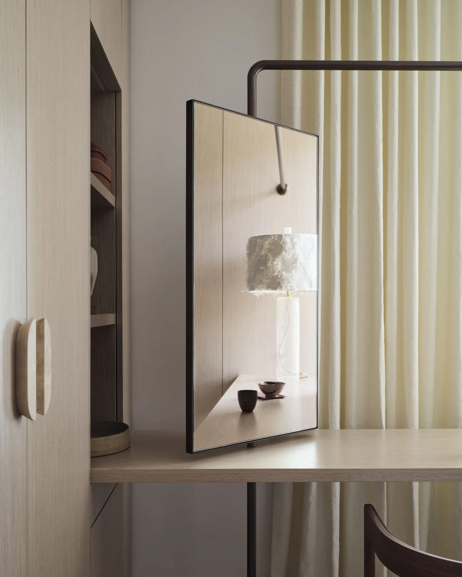 Modern home office with a wooden desk, lamp, and curtain.