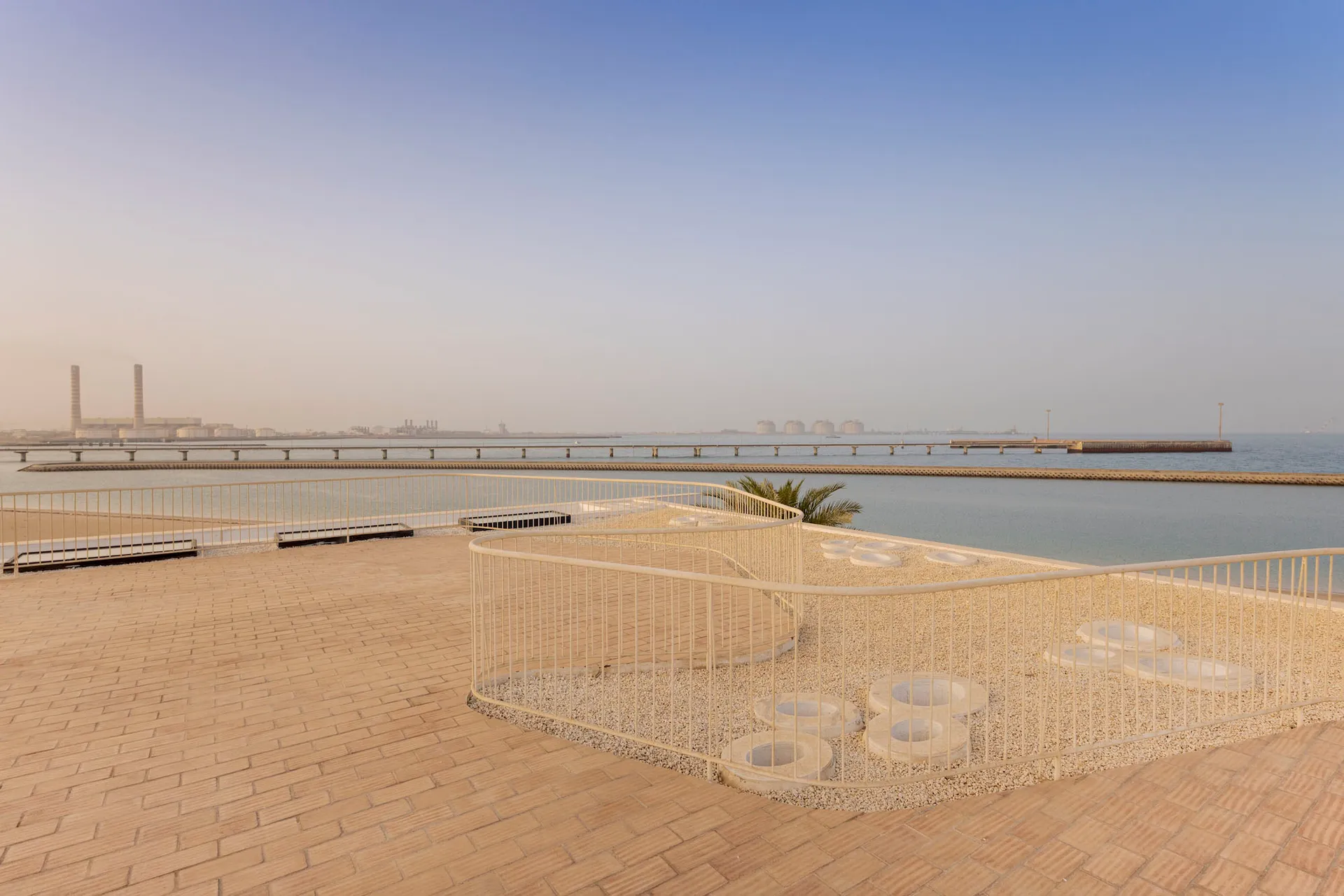A sand-covered balcony overlooking the sea with a railing and a few circular platforms.