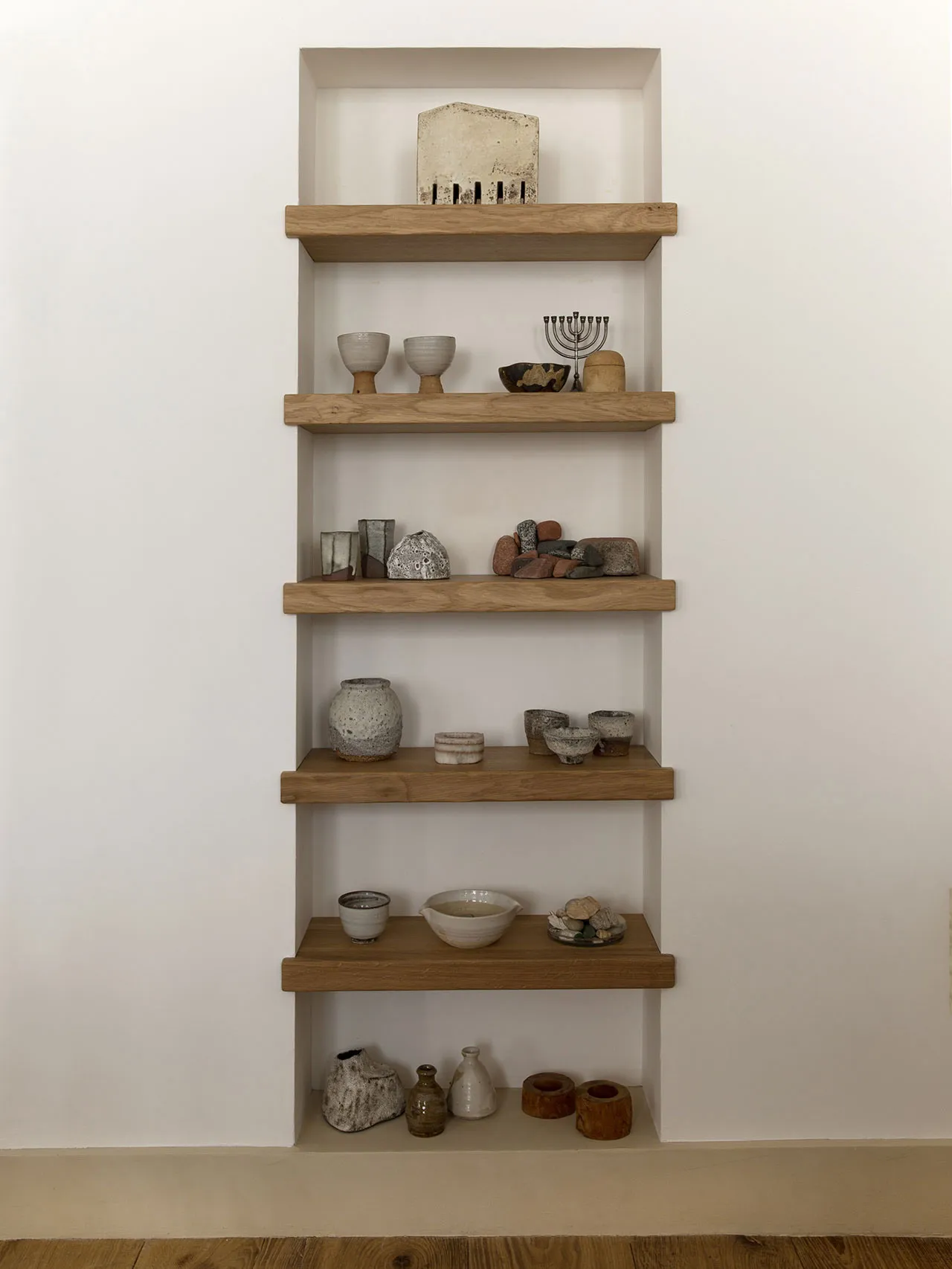 A collection of various ceramics and rocks displayed on wooden shelves.