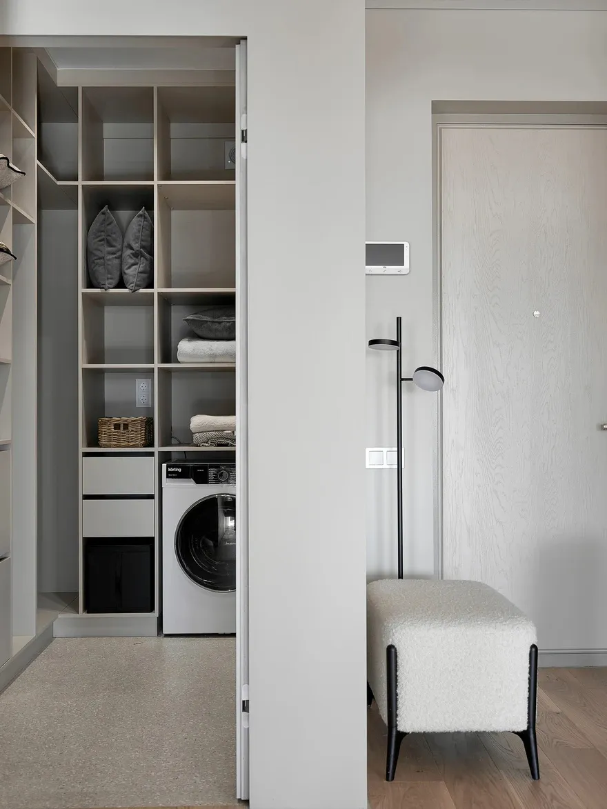 A modern closet laundry room featuring a white column and a wooden floor.