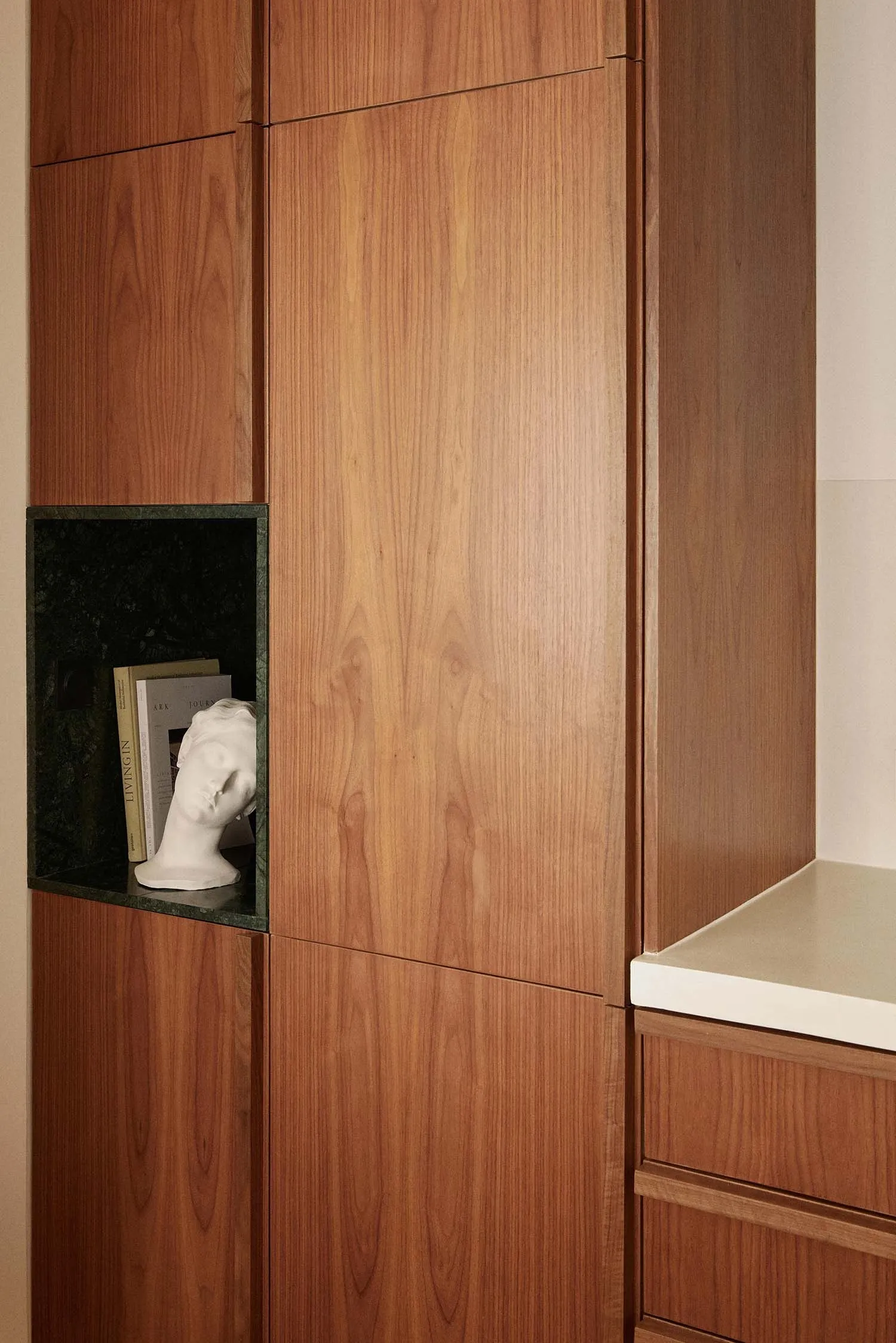 Modern wooden storage unit with a niche for books and a bust sculpture.