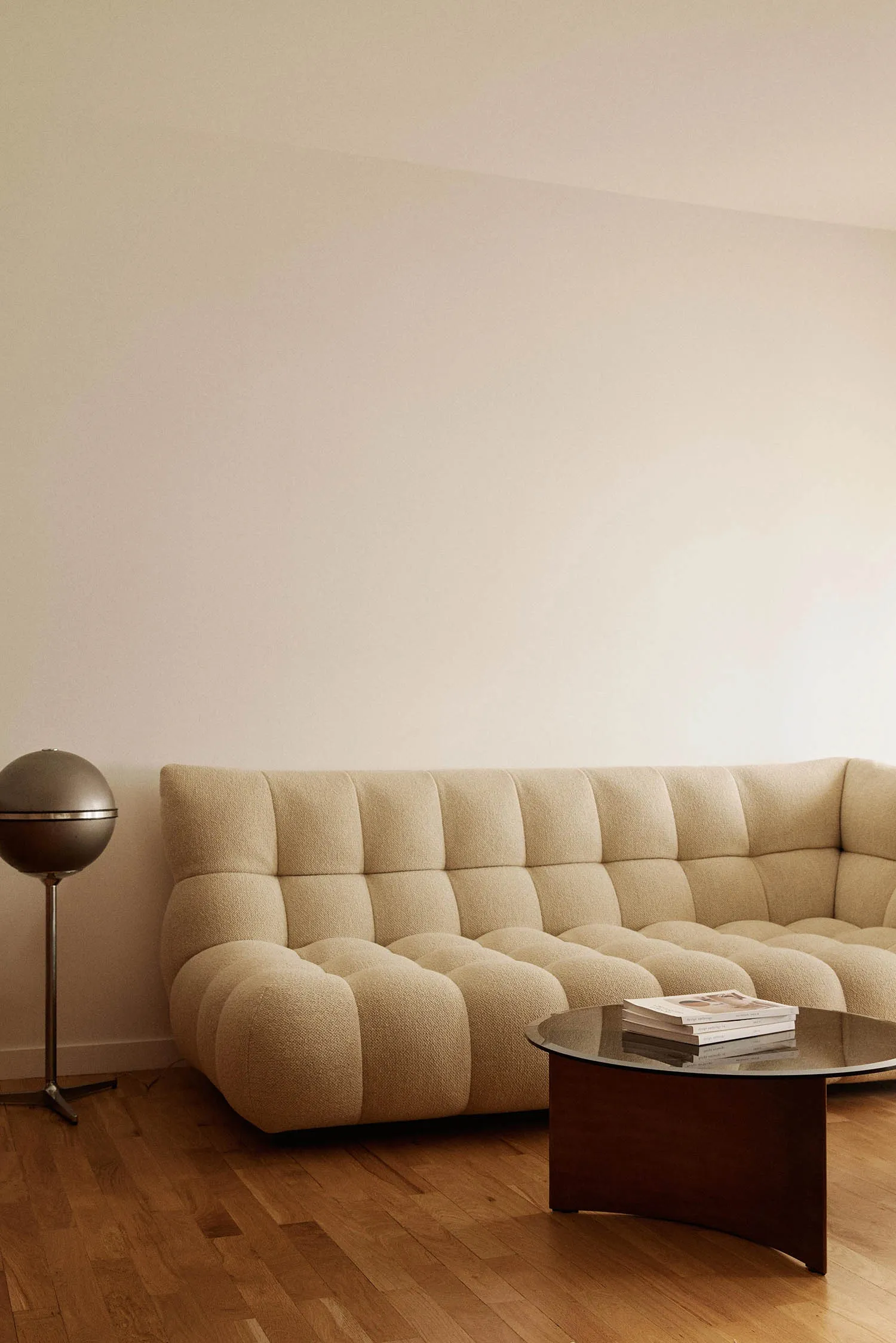 A modern living room featuring a cushion sofa upholstered in white fabric with a patterned texture, set against a minimalist