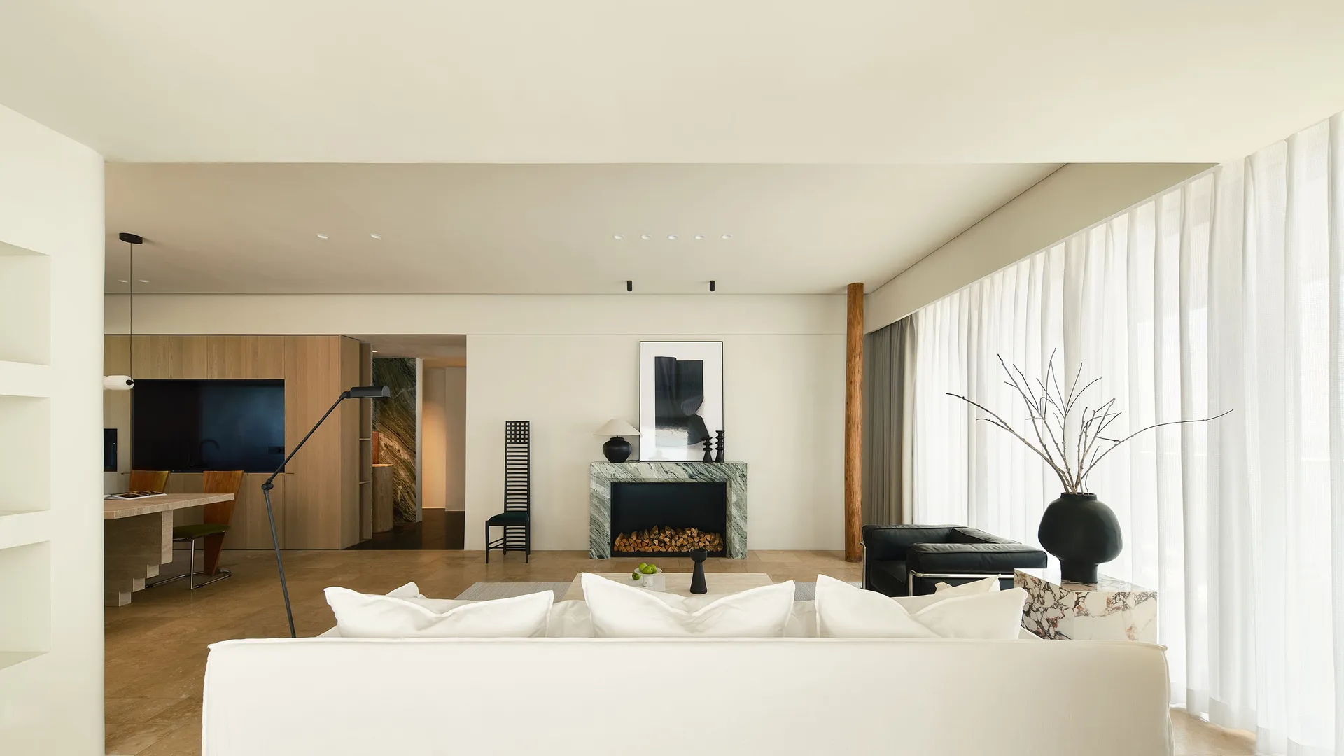 Modern living room with white sofa, marble fireplace, and large windows.