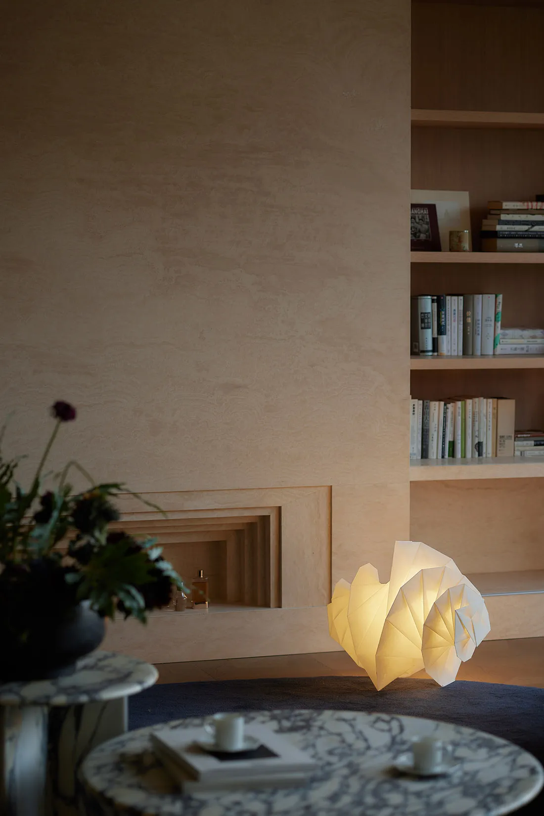 A minimalist living room featuring a uniquely designed paper table lamp emitting a warm glow.
