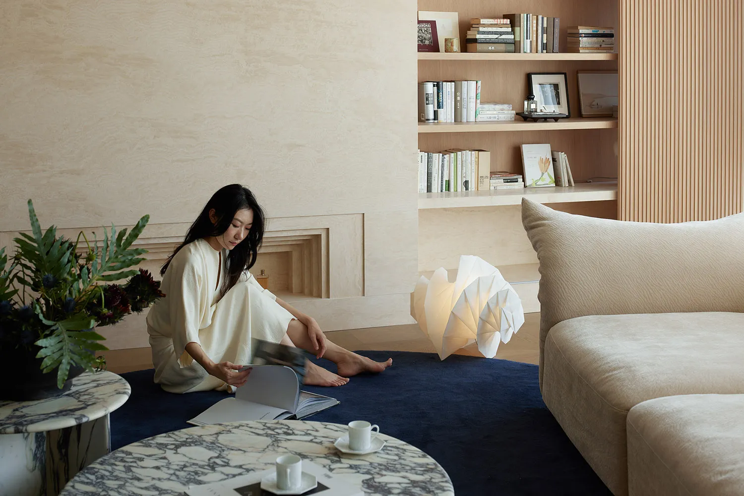A modern living room with a textured cloth sofa and bookshelf filled with books and decorative items.