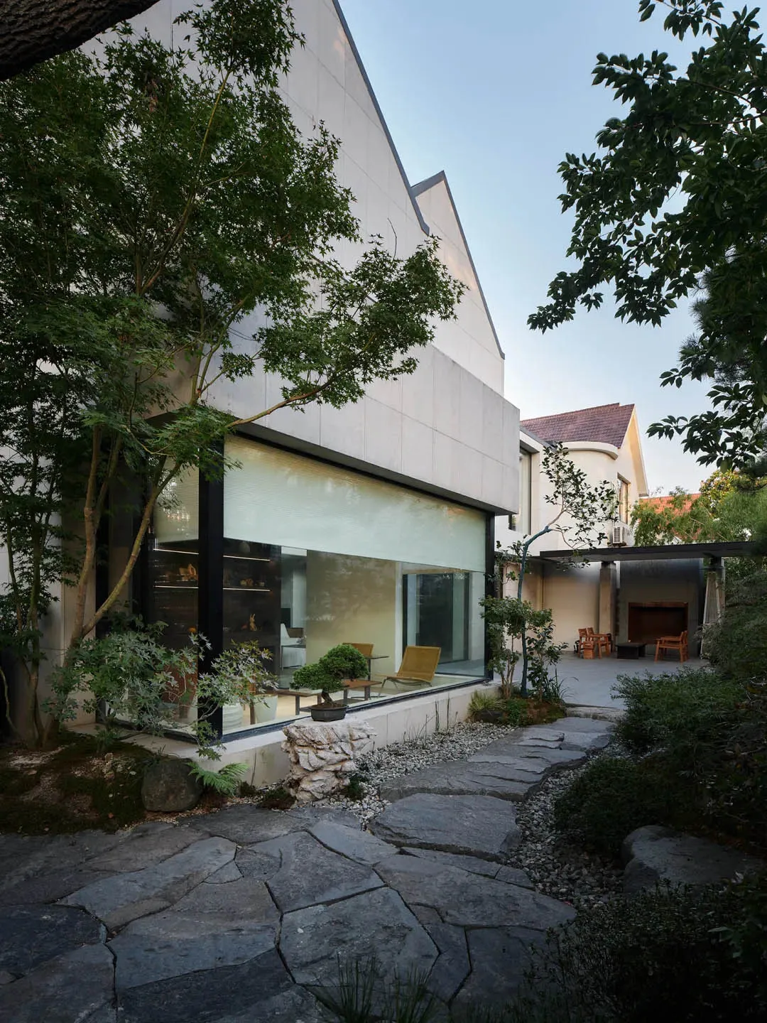 現代住宅外觀採用混凝土立面、大型玻璃窗,以及通往入口的石板步道。