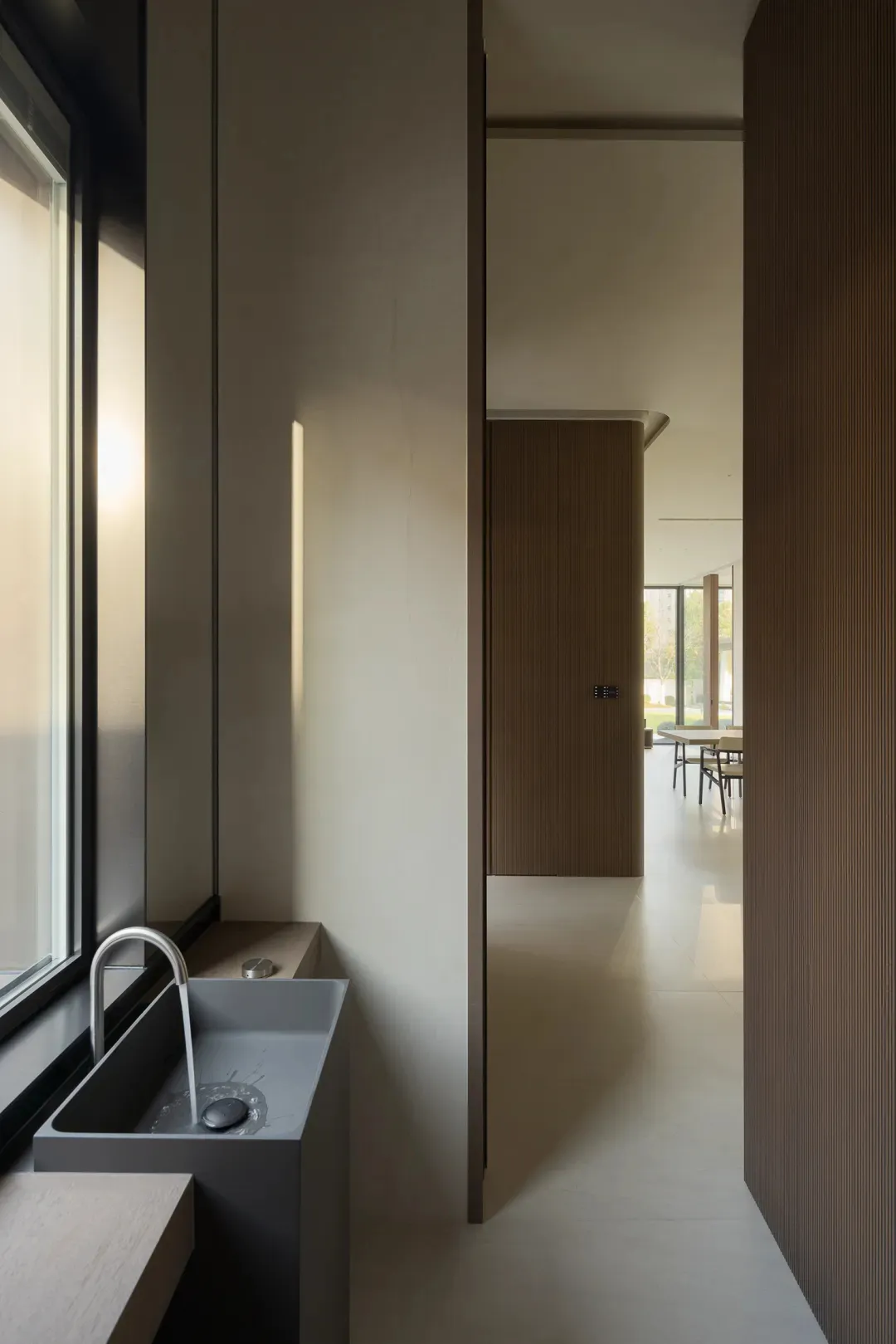 A minimalist bathroom features a concrete sink and a window with natural light.