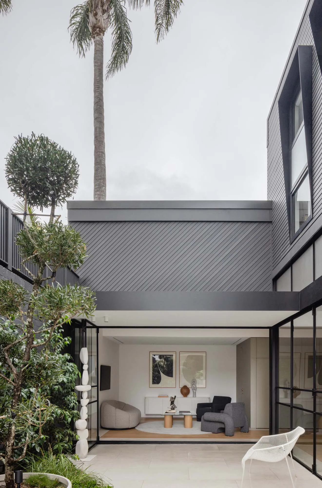 Modern, minimalist living room with concrete walls, sleek furniture, and large windows.