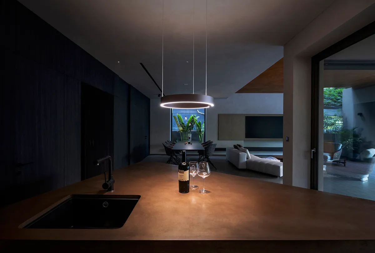 A modern kitchen with a concrete countertop and a black sink.