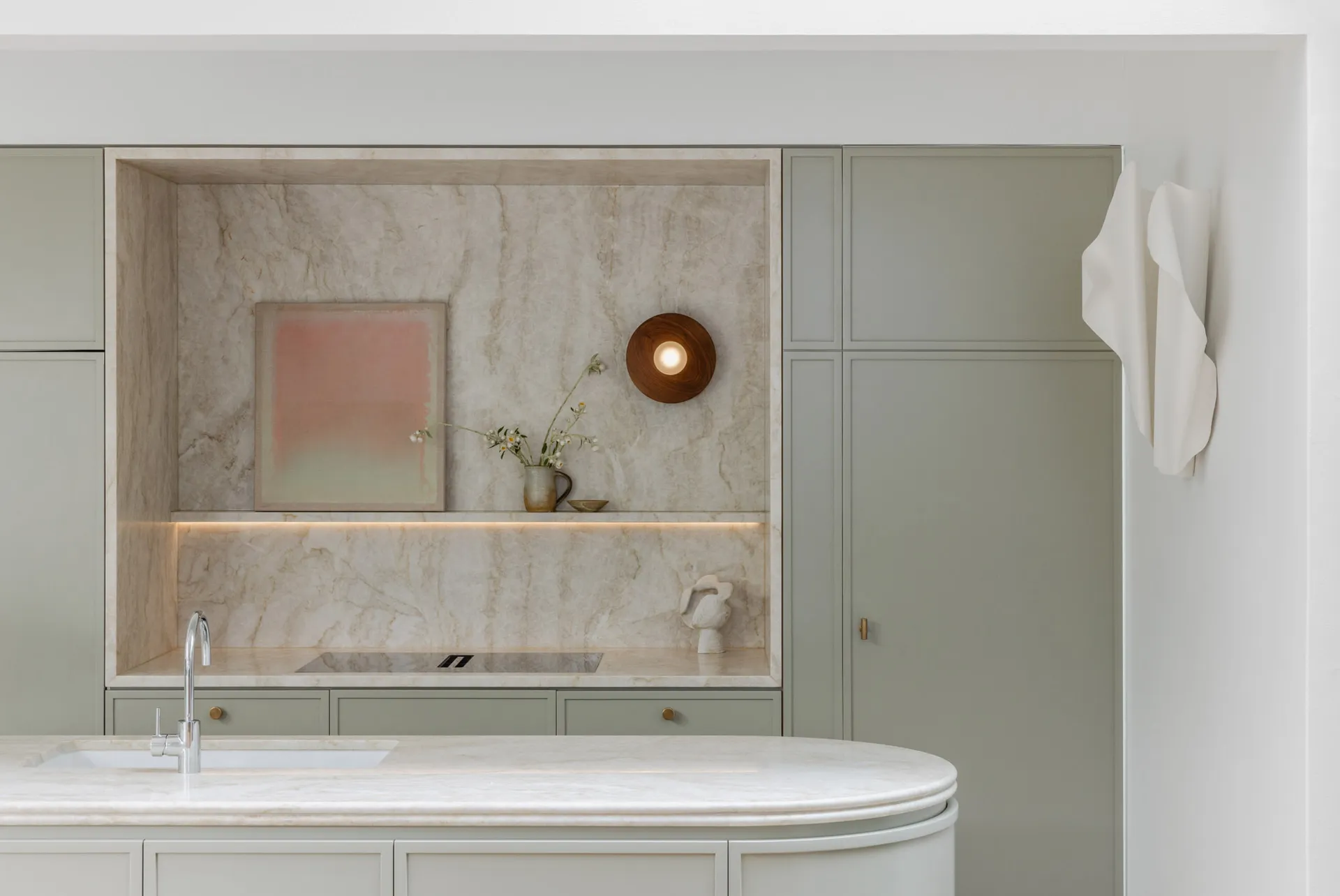 An elegant, minimalist kitchen featuring a marble countertop and backsplash with soft lighting and subtle decorative elements