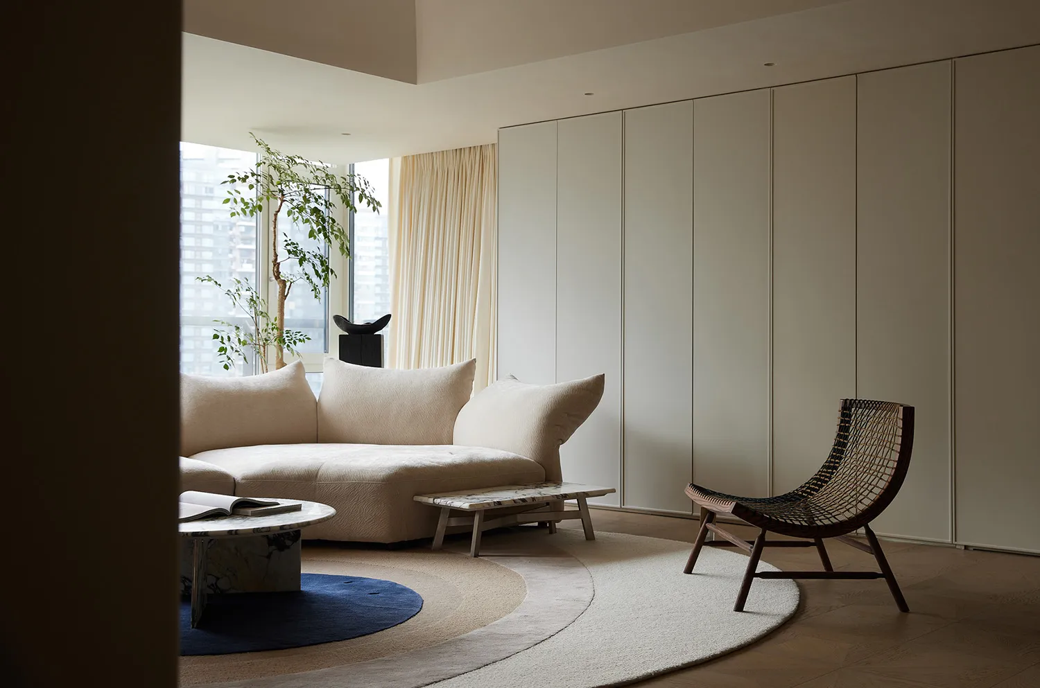 A modern living room with a neutral-toned color palette, featuring a contemporary sofa, minimalist coffee table, and a natura