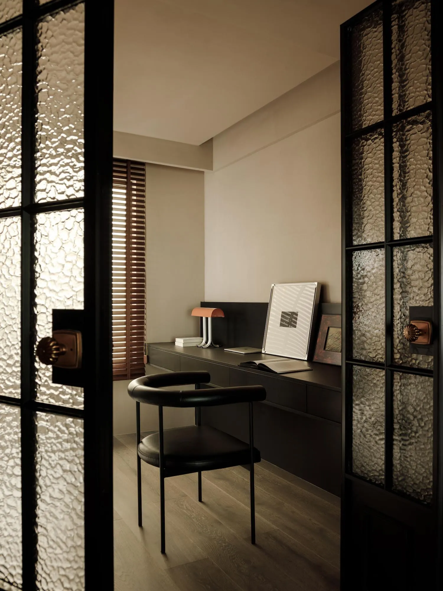 Minimalist home office with industrial design elements, featuring wooden furniture and a black chair.
