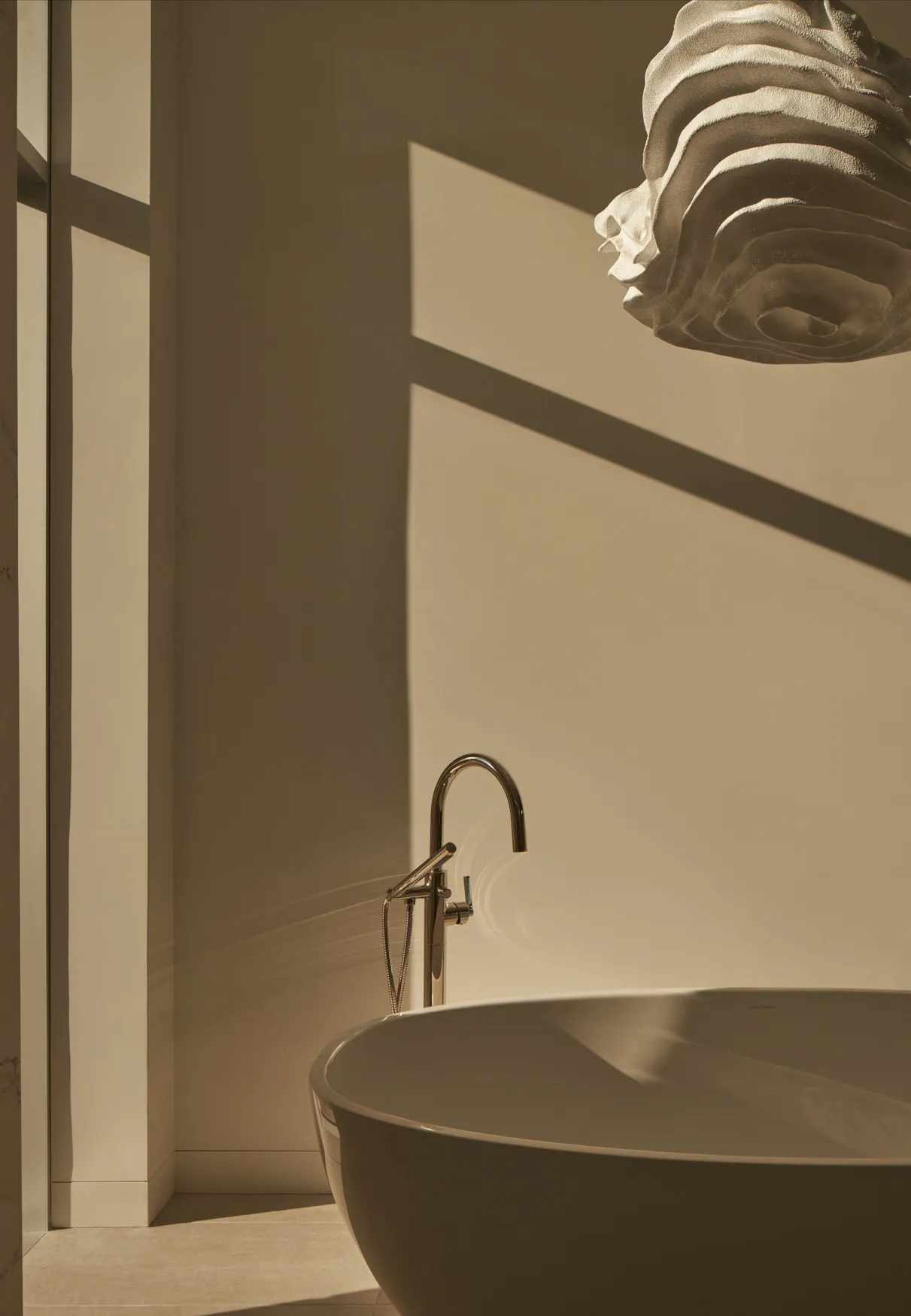 Modern bathroom featuring a sleek, ceramic free-standing tub with a minimalist design and natural light streaming through the