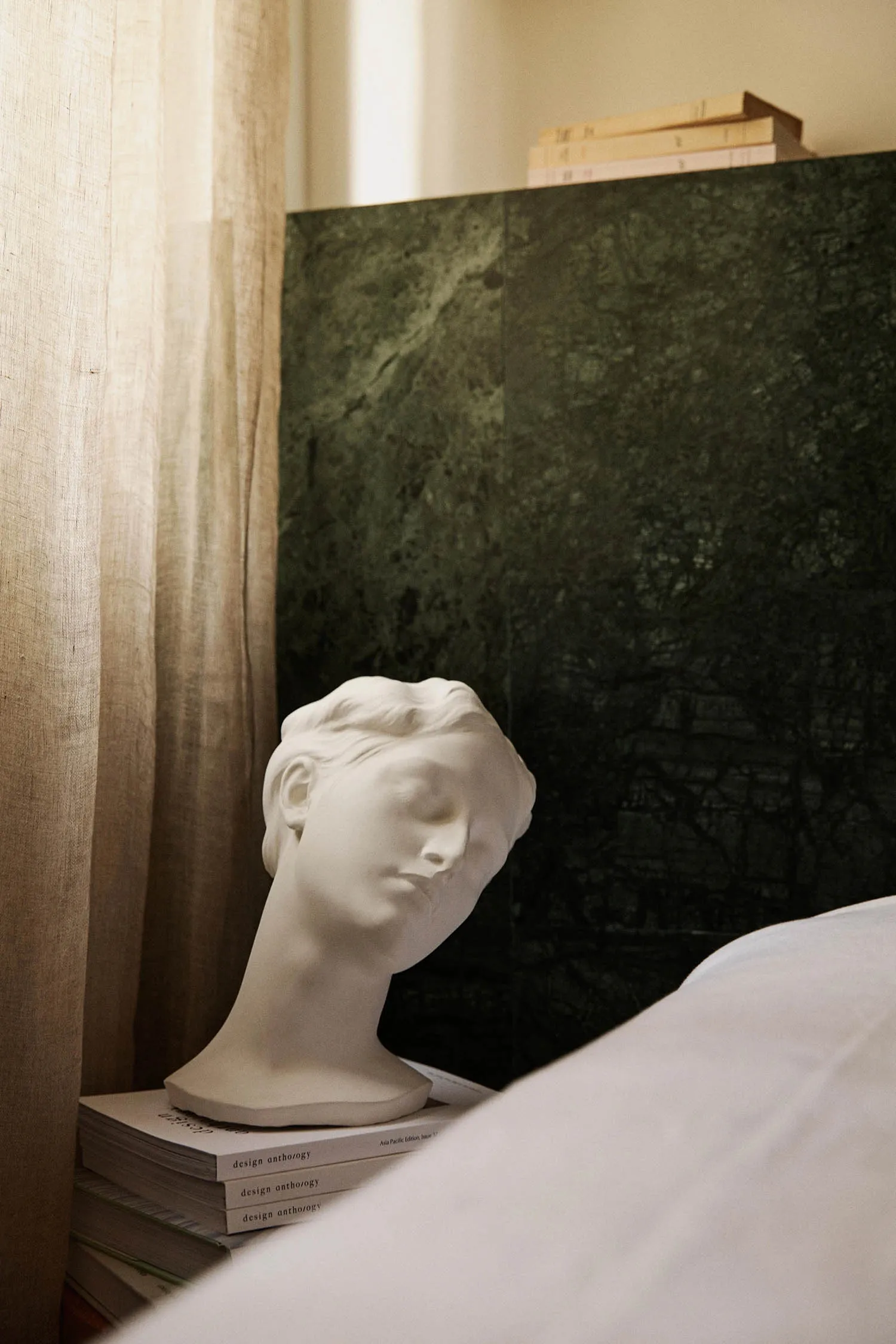 A modern bedroom showcasing a stone head sculpture on books.