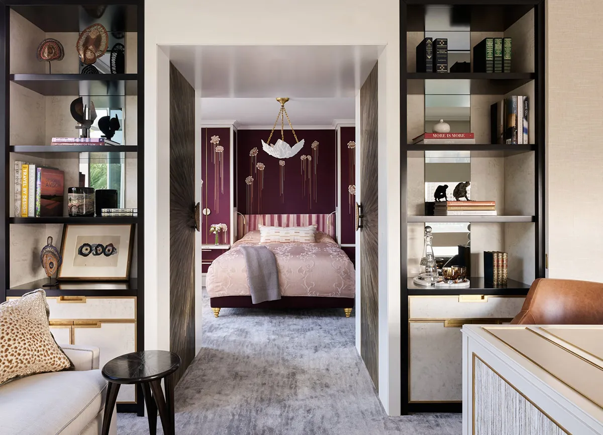 Modern, purple-themed bedroom suite with a chandelier, bed, and bookshelves.