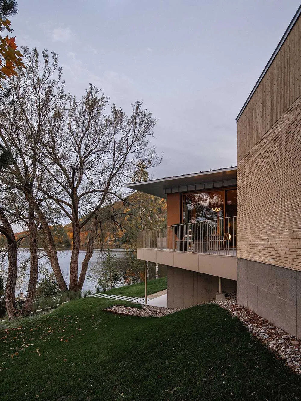 Modern house with a brick exterior overlooking a lake.