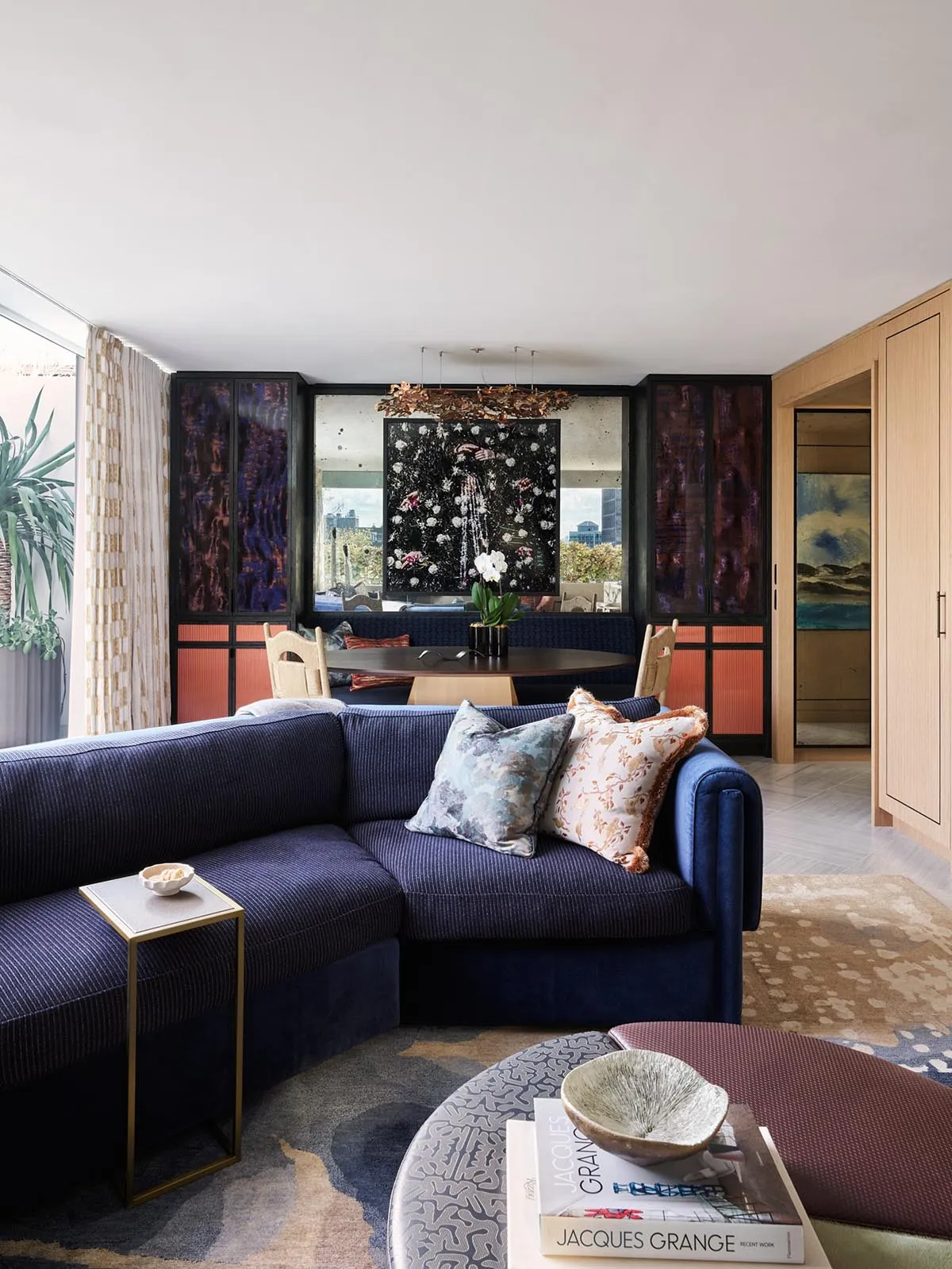 A modern living room with a navy blue sofa, patterned rug, and abstract art on the wall.