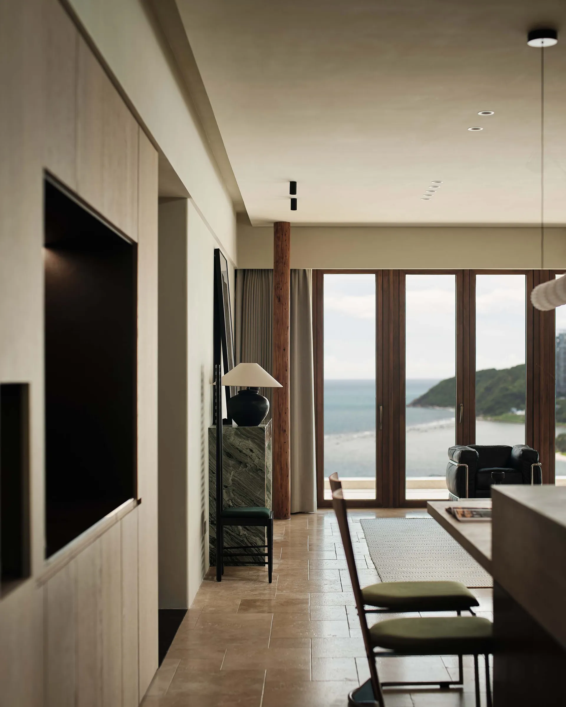 Modern living room featuring ocean views with wooden flooring, steel accents, and marble finishes.