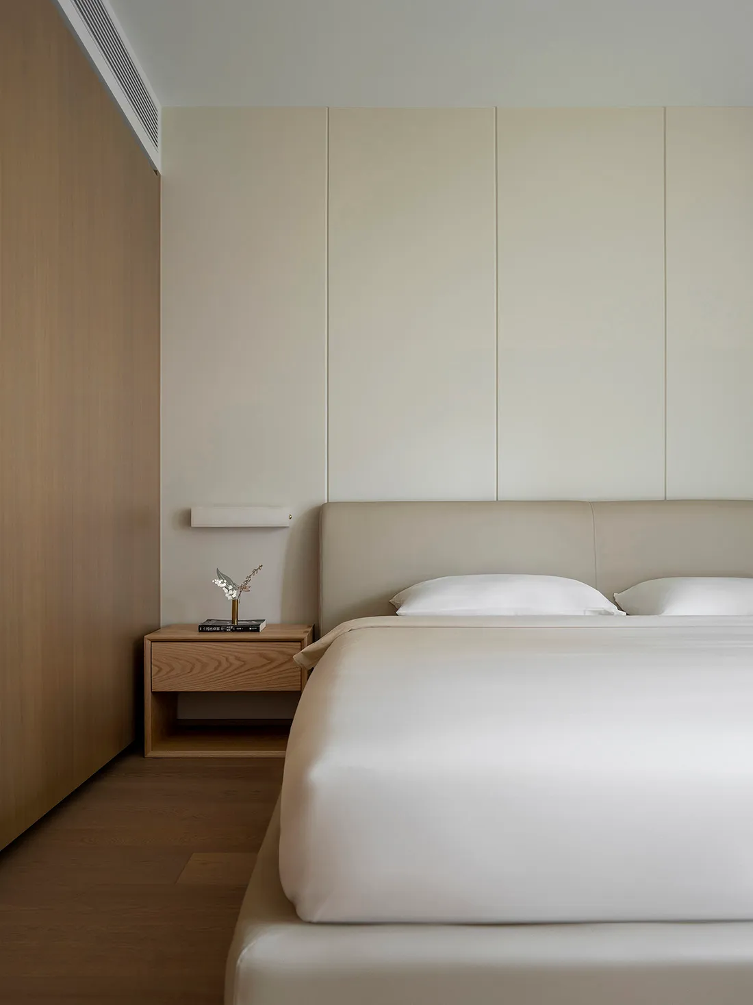 A modern minimalist bedroom with neutral tones and wood accents.