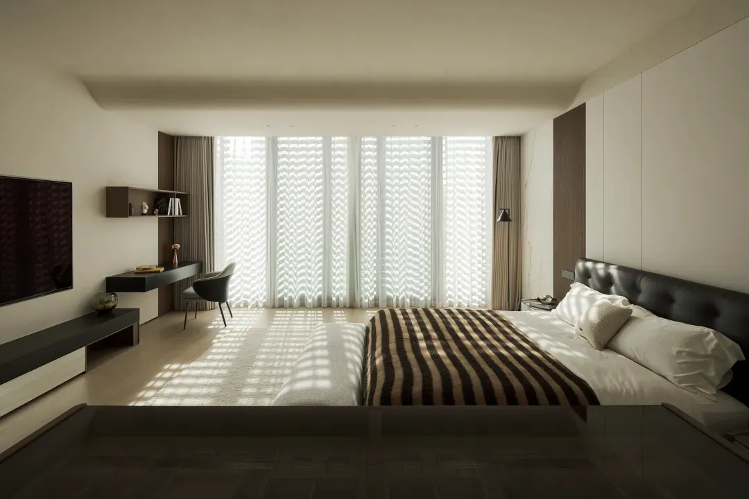 Modern minimalist bedroom with large window, striped blanket, and sleek, black furniture.