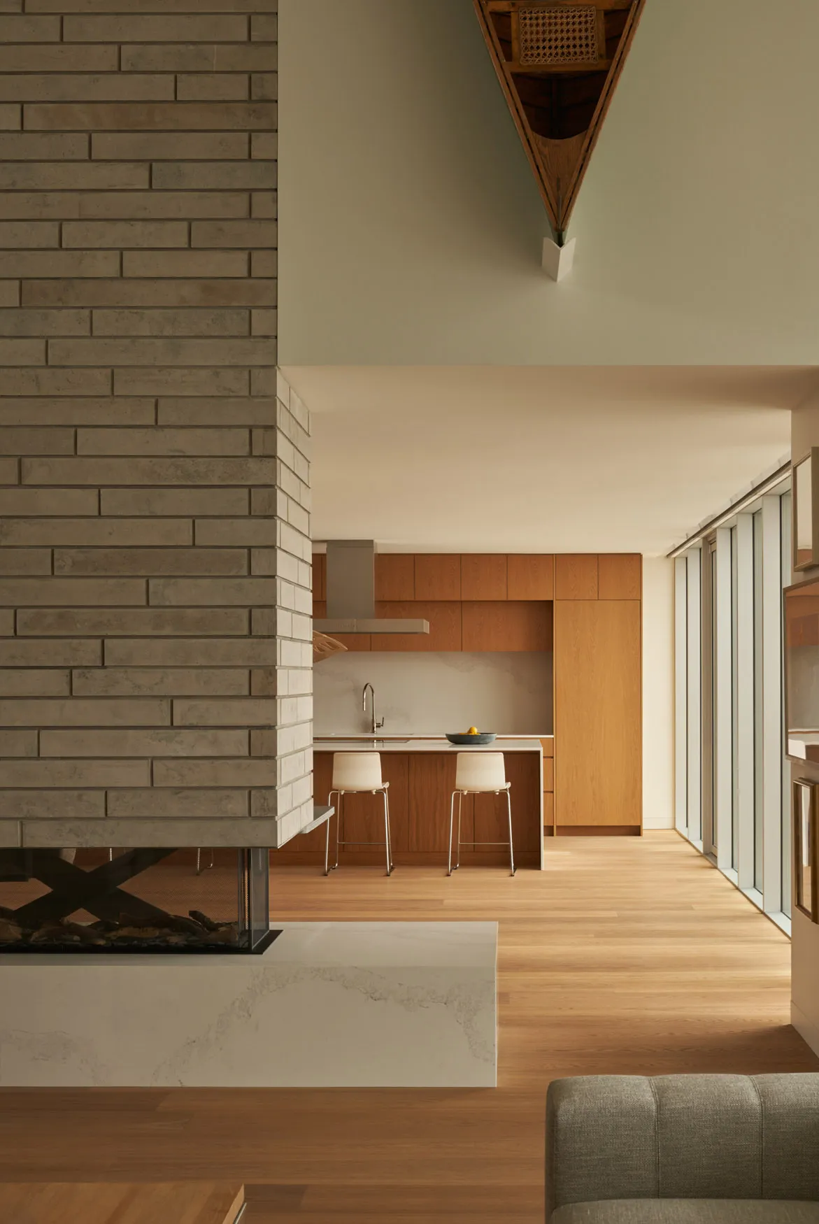 A modern residential kitchen features brick walls, wooden cabinets, and marble countertops.