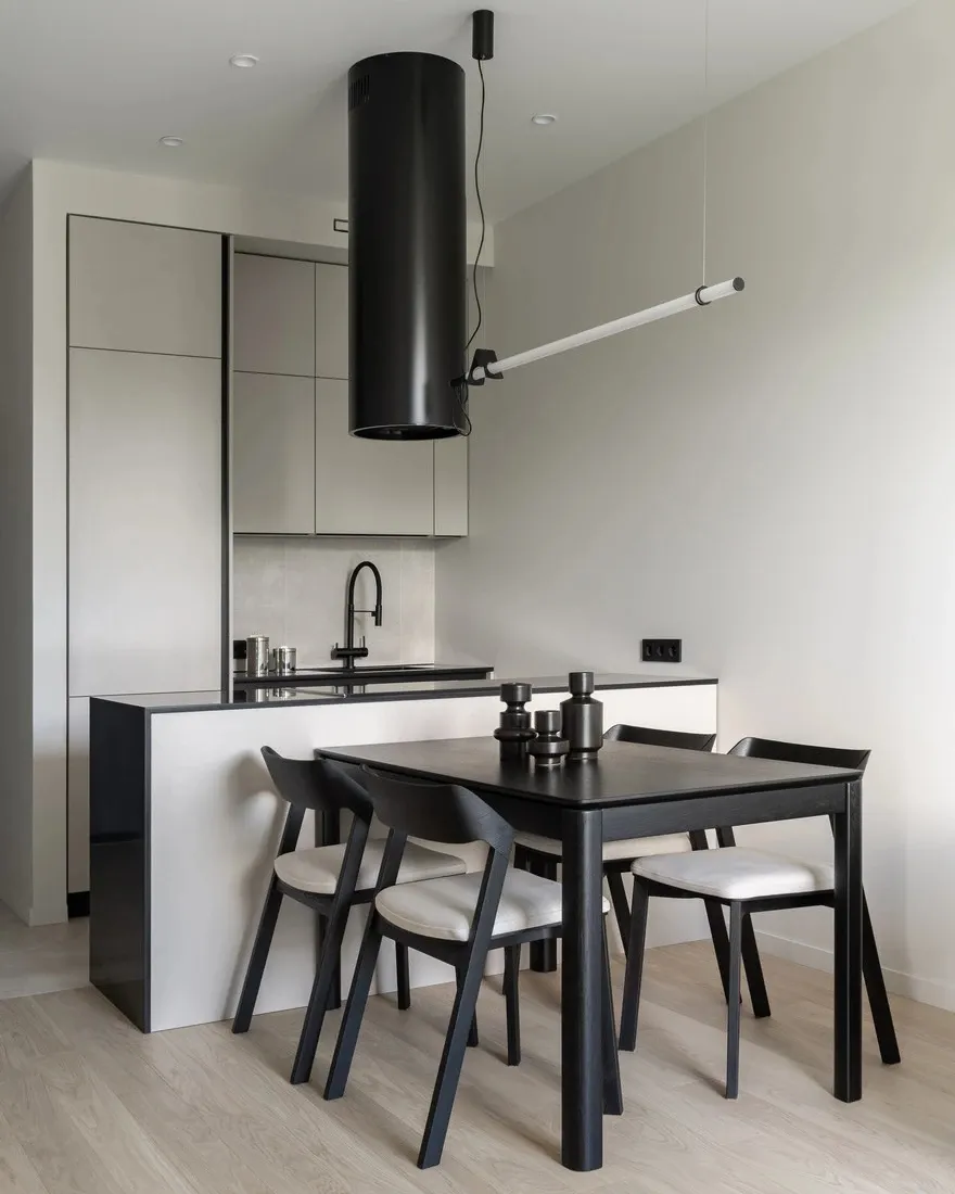 Modern kitchen with minimalist design featuring white glass cabinets, black kitchen island, and black dining table with white