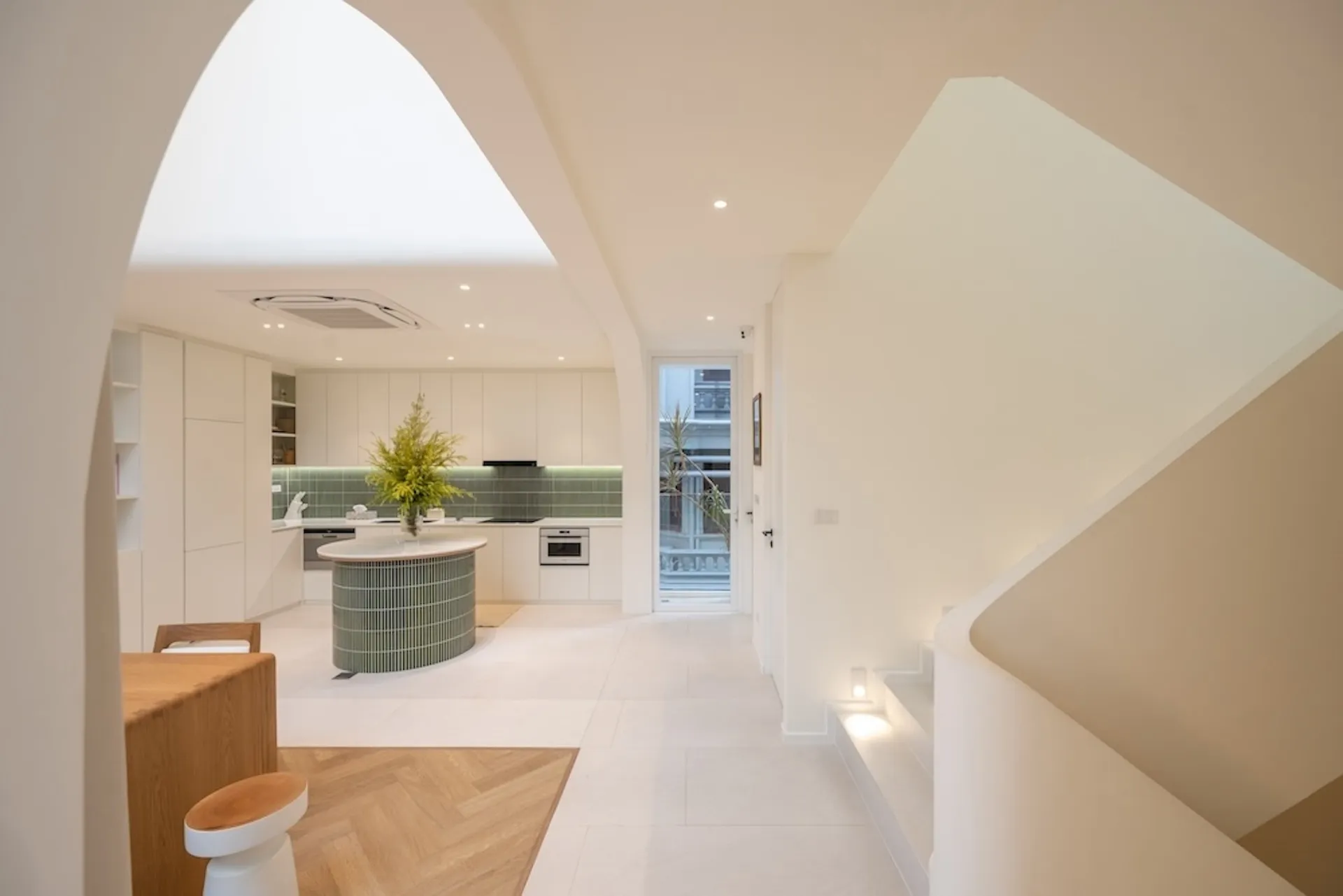 A minimalist kitchen with white cabinets and a green island.