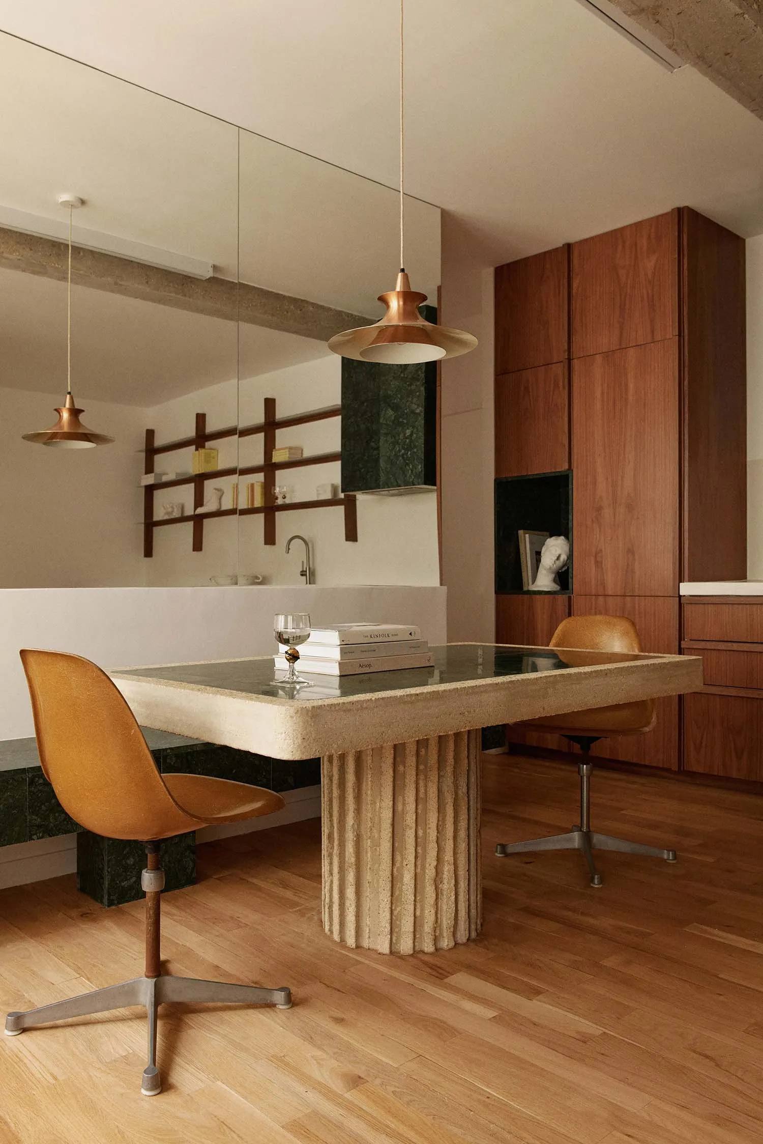 Modern kitchen with concrete and marble table, chairs, and pendant lights.