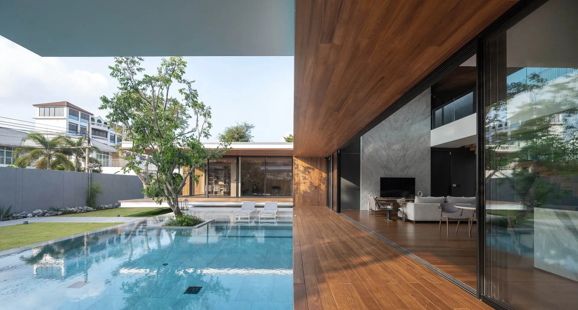 Modern minimalist residential interior featuring wooden floors, glass walls, and marble accents.