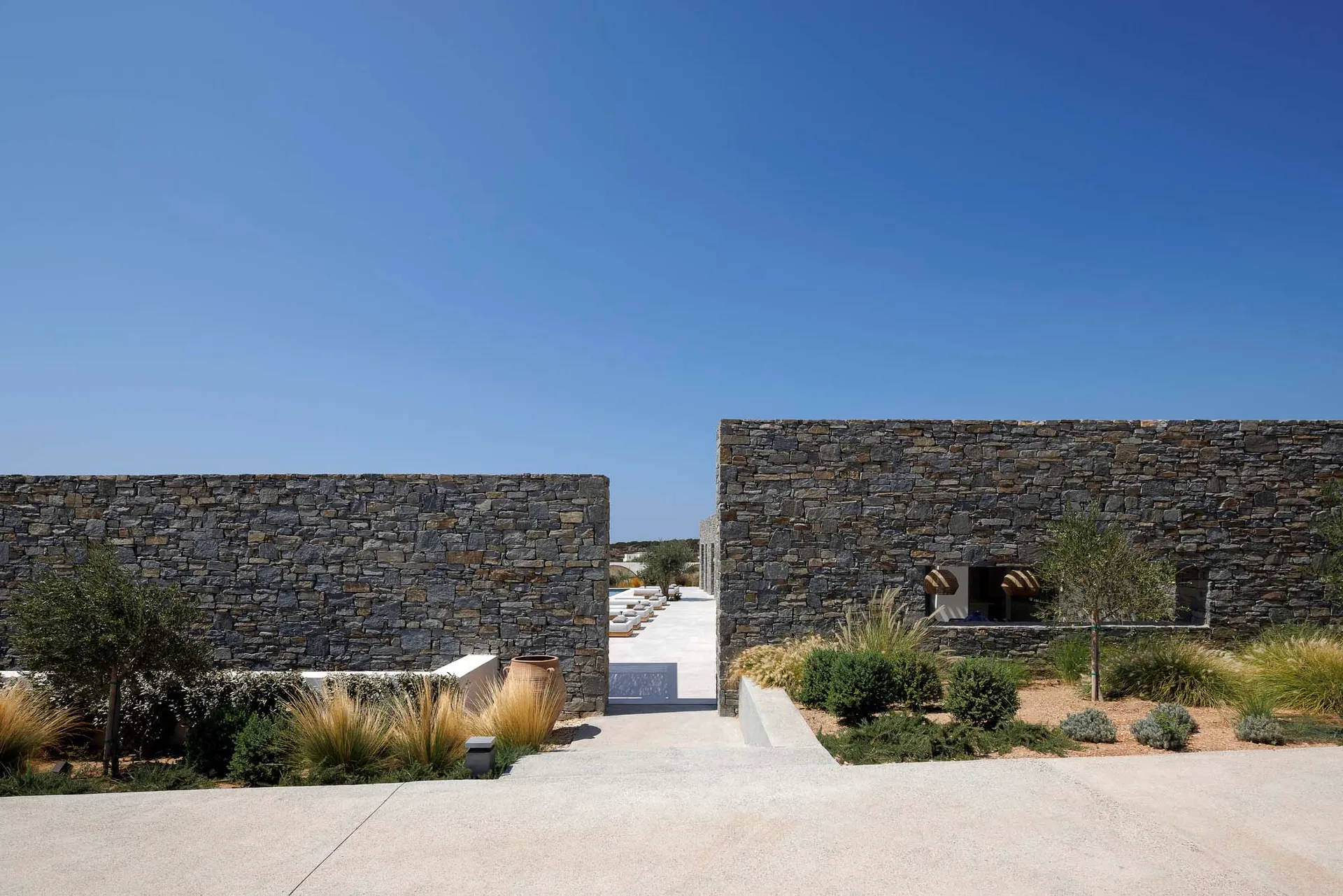 A modern residential exterior featuring stone walls and a clear blue sky.