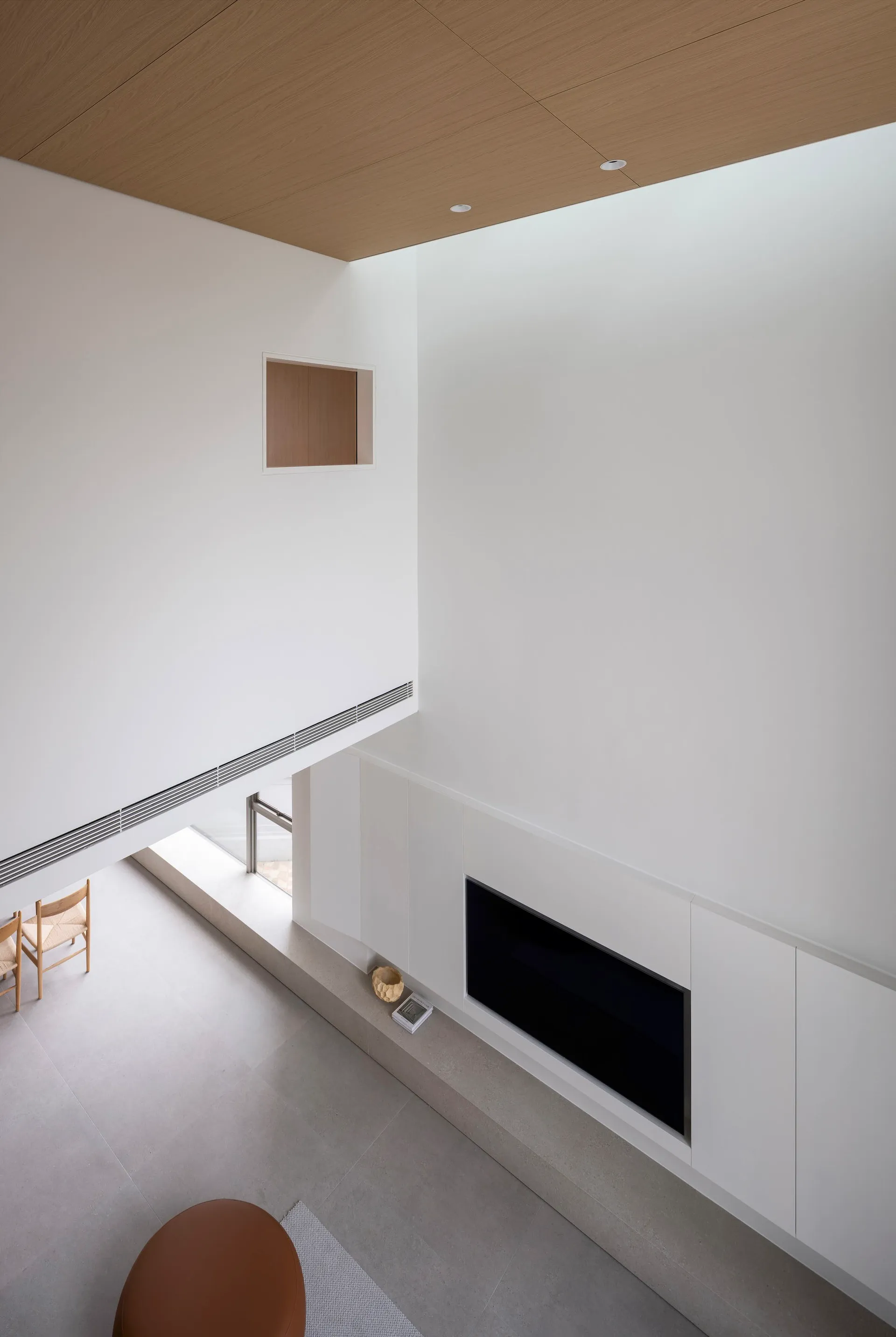 A minimalist living room with white concrete walls, wood ceiling, and a sleek fireplace.