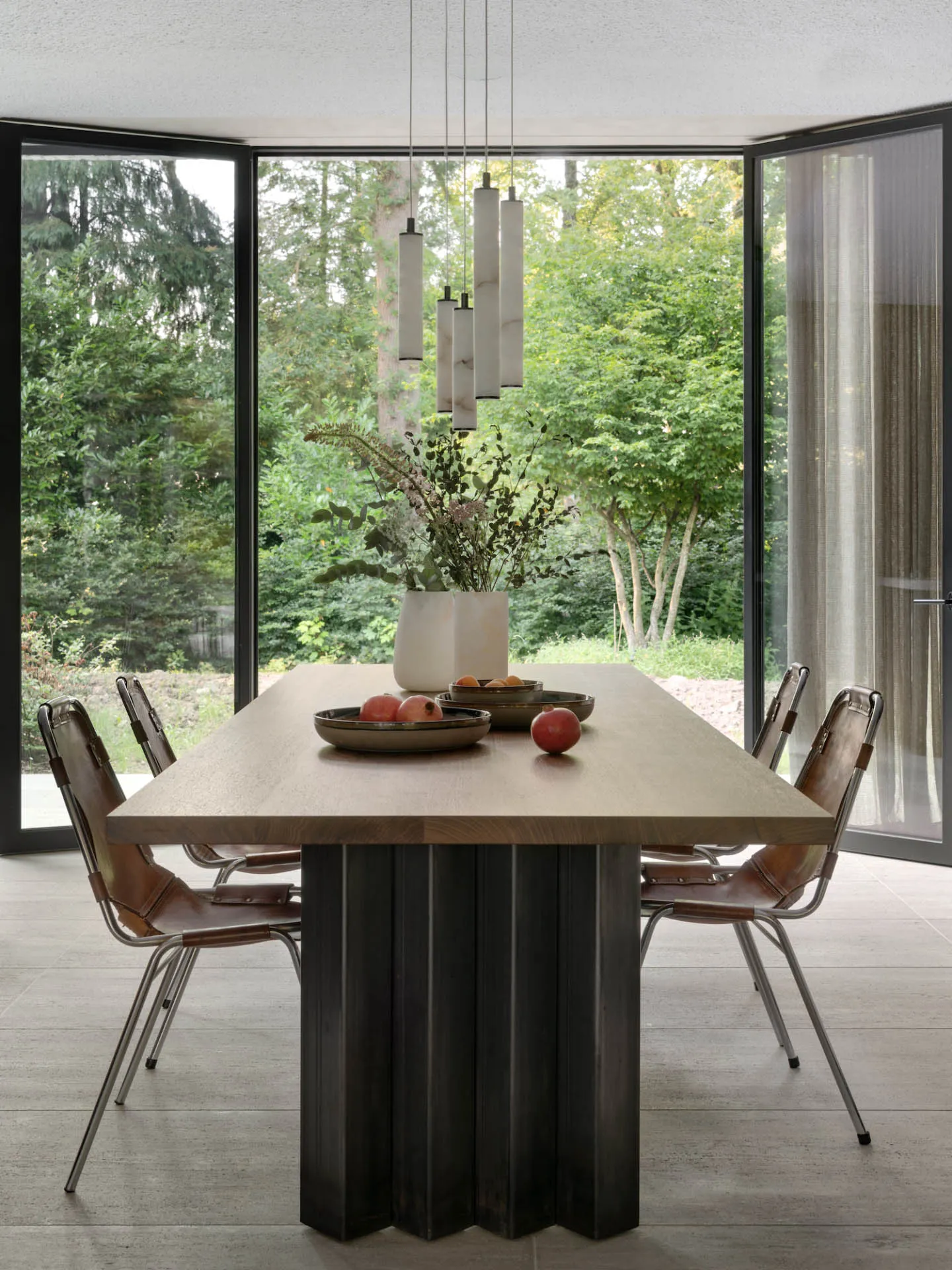 Modern dining room featuring a wooden table set with fresh apples and flowers.