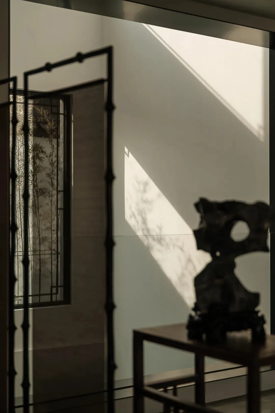 A modern entryway with wooden features and a shadowed bamboo plant in the background.