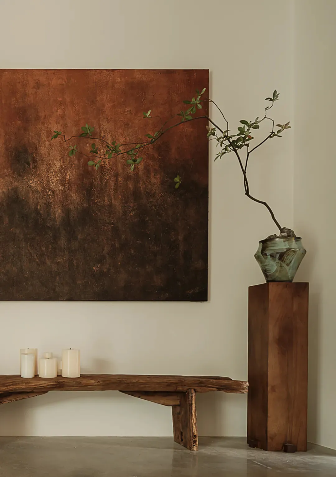 Modern interior design featuring wooden bench, stone vase, and metal vase with greenery.