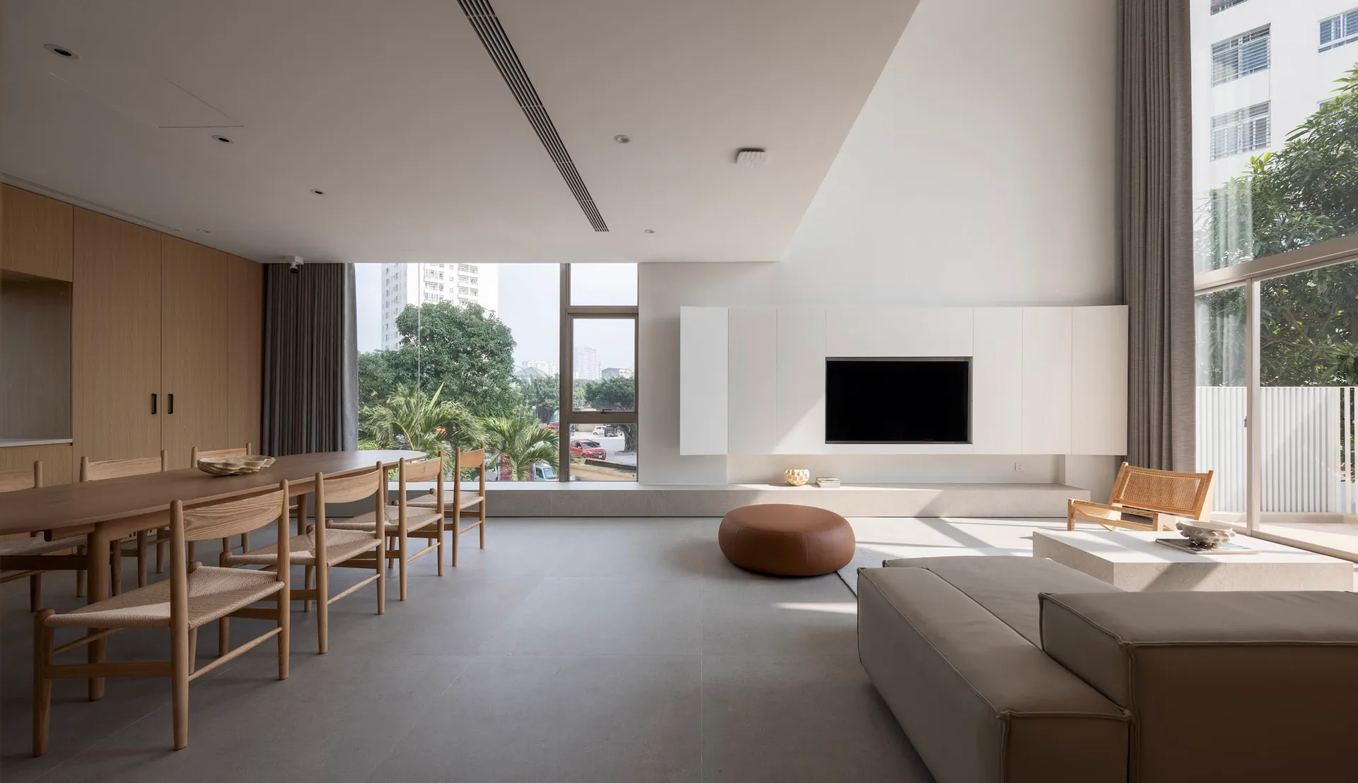 A modern living room featuring minimalistic furniture and a large wooden table with chairs.