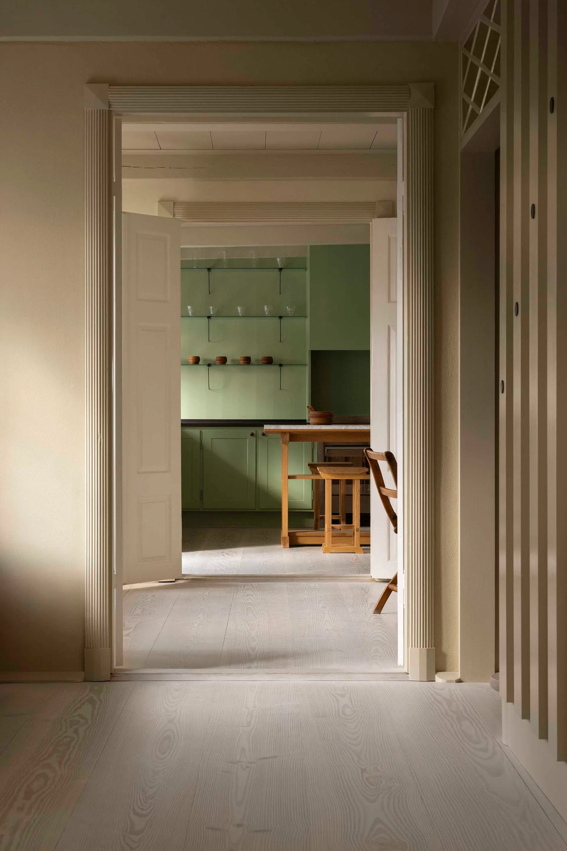 A minimalist residential kitchen with wooden elements and a light wood floor.