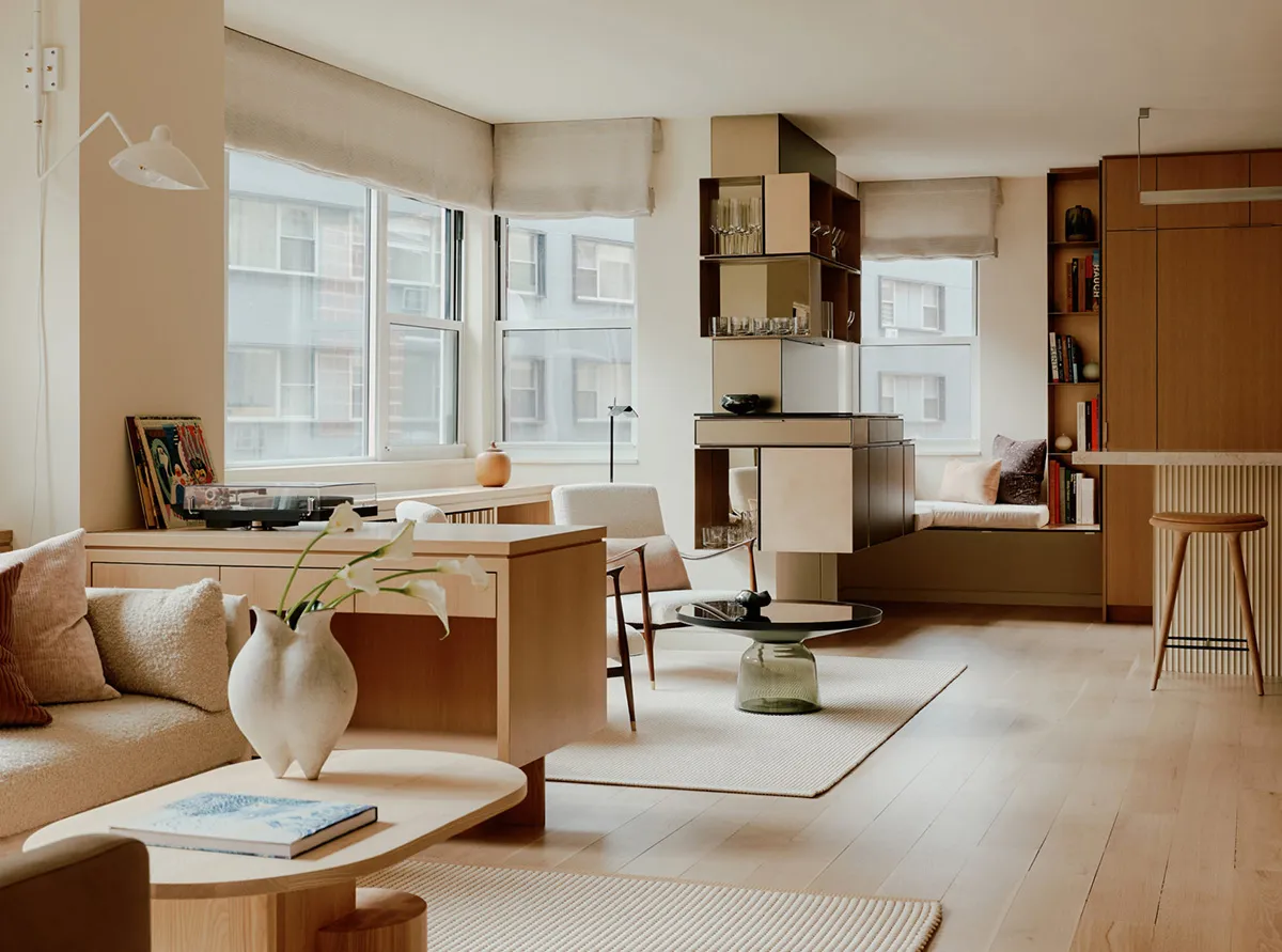 Modern minimalist living room with brown wooden furniture, white accents, and large windows.