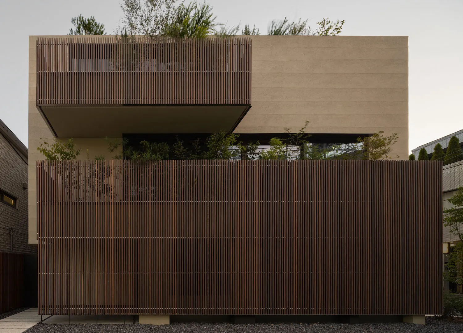 A modern house exterior featuring a wood slat fence and greenery.