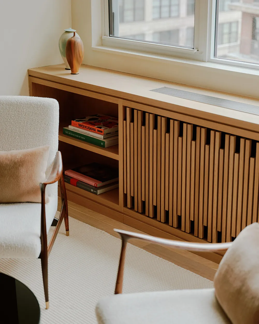 A modern interior design featuring wooden shelving and a window with books and a vase on the sill.