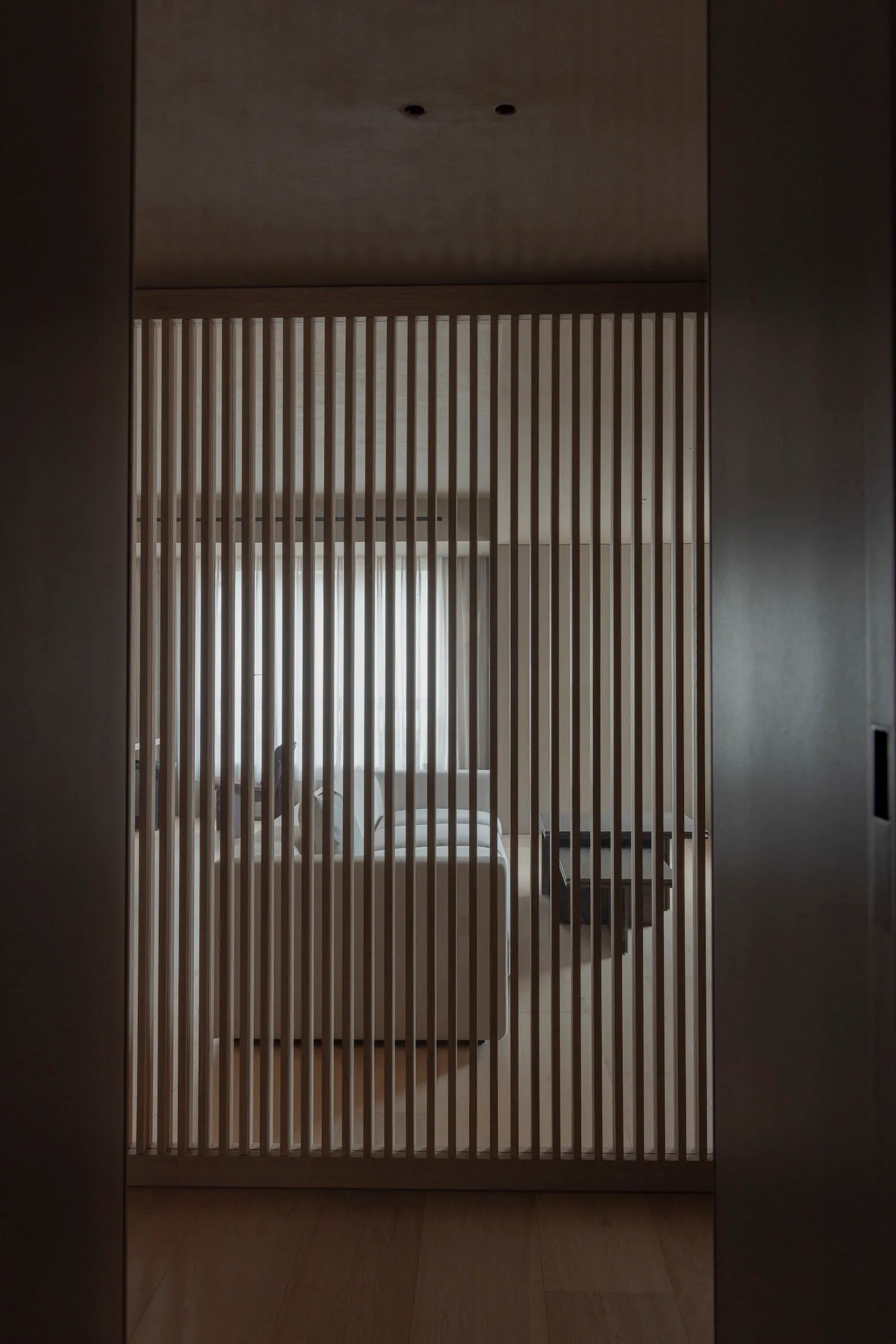 A view of a minimalist bedroom with a wooden room divider.