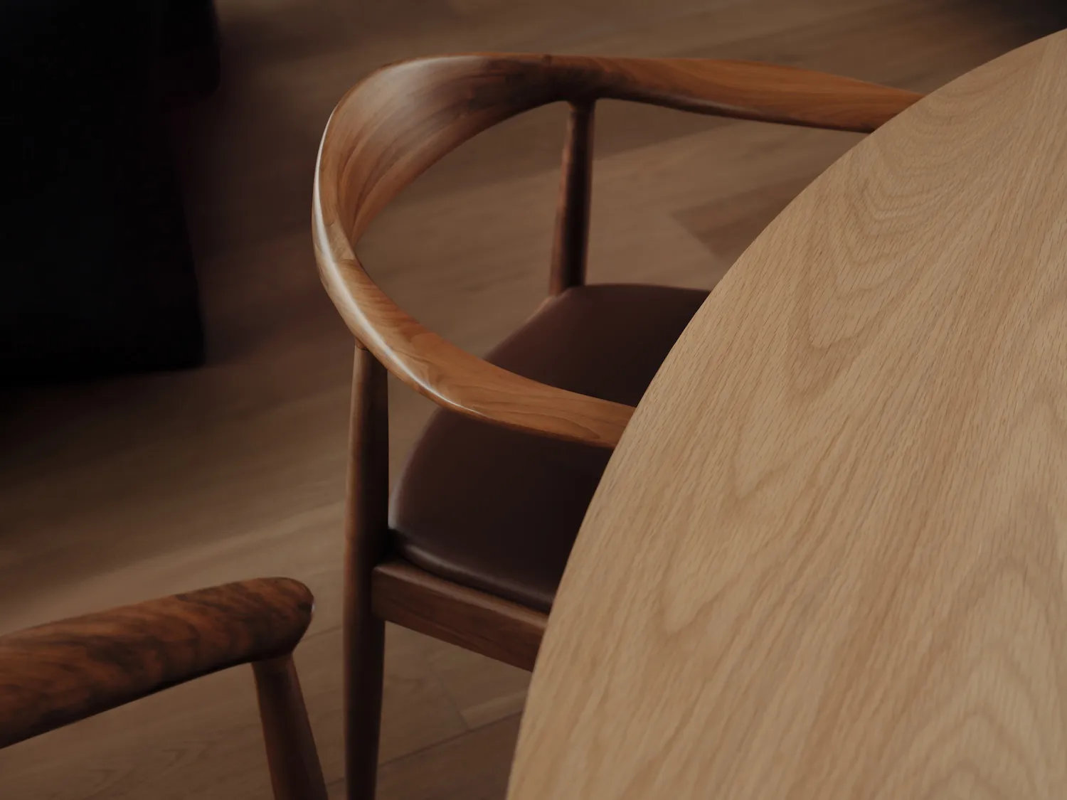 A round wooden table with matching chairs, showcasing a sleek, curved design.