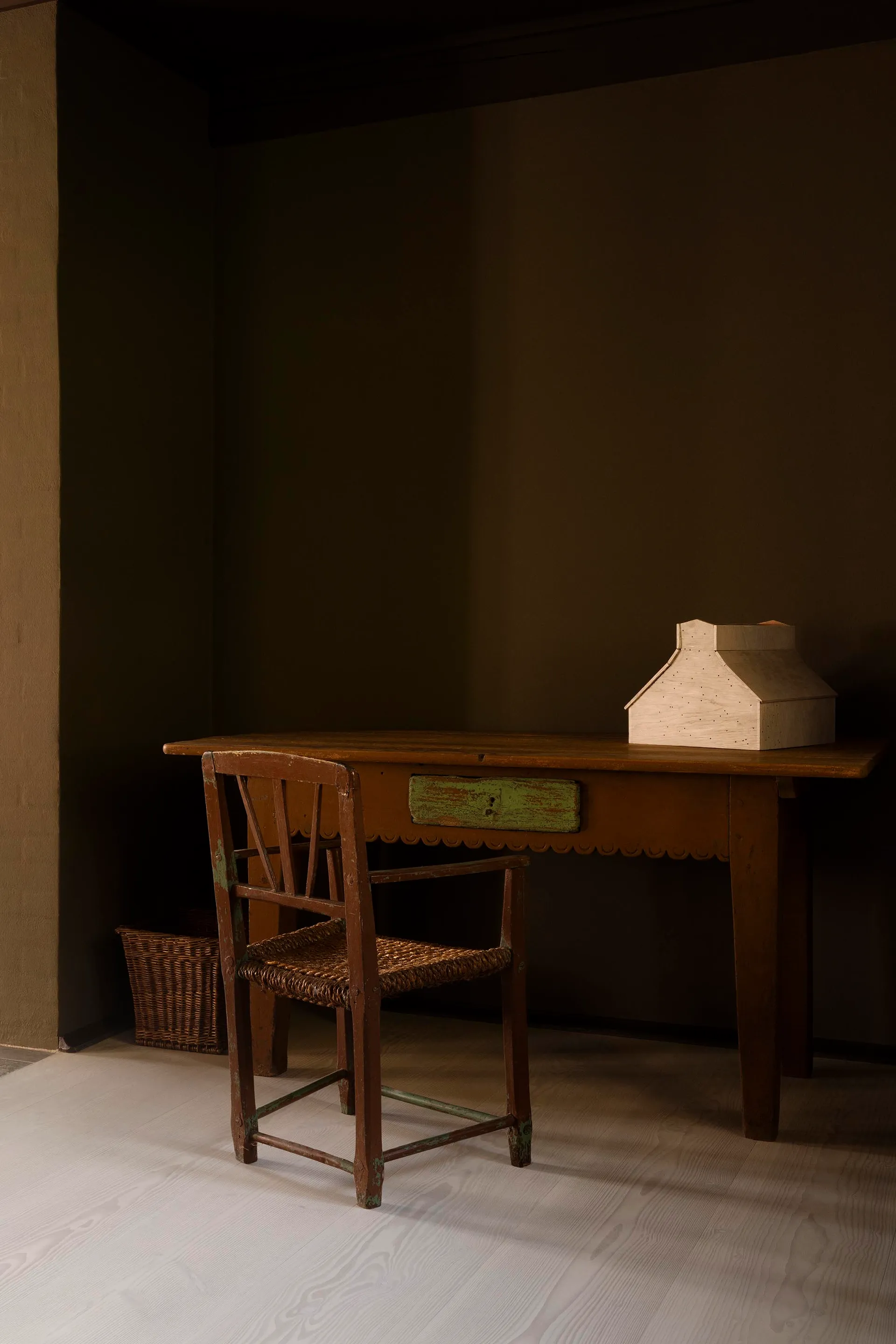 A rustic wooden table and chair in a cozy home office setting.