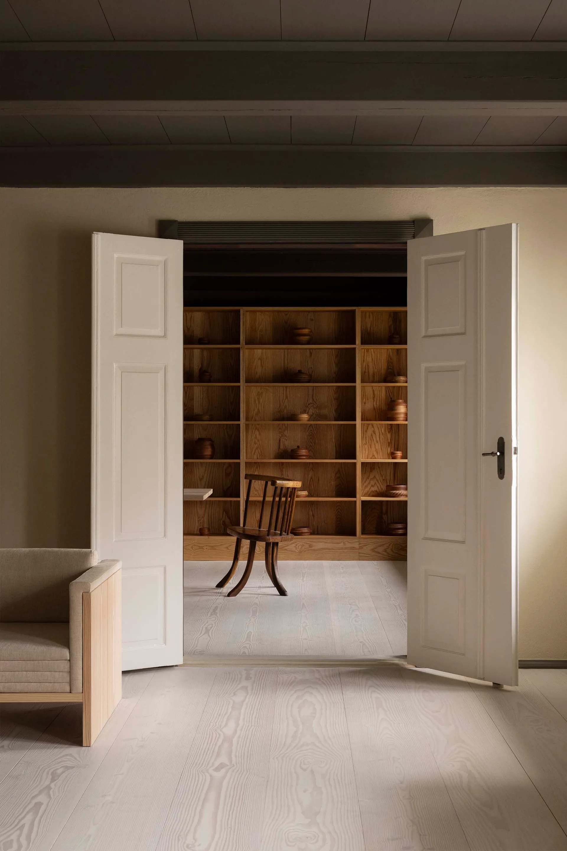A minimalist library featuring wooden shelves with various pottery items on display.