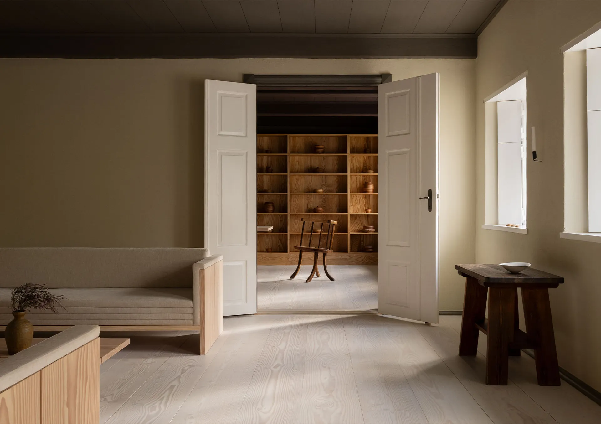 Minimalist living room featuring wooden furniture and a bookshelf filled with wooden pots.