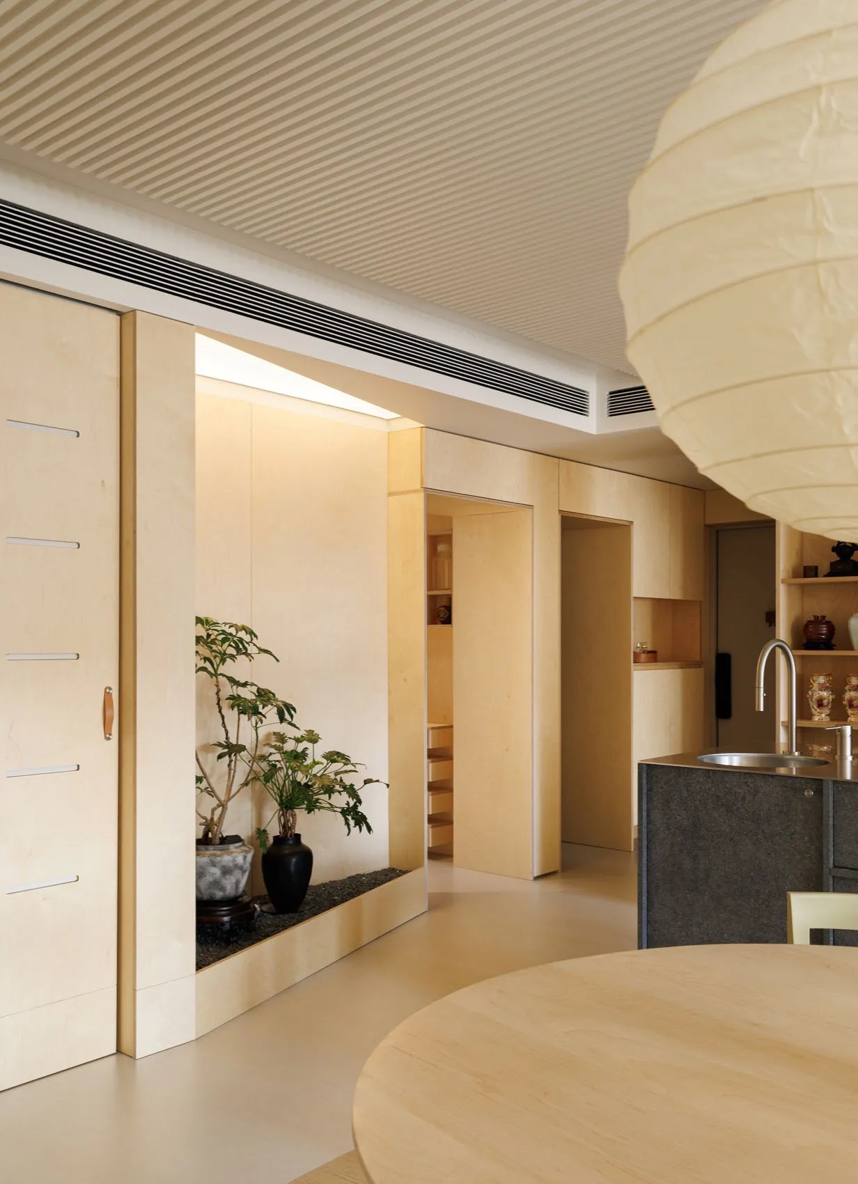 A modern apartment with minimalist design, featuring wooden interiors and a round table.