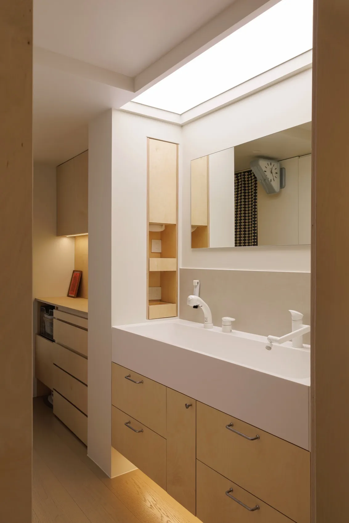 Modern minimalist bathroom with a white porcelain sink and wooden cabinets