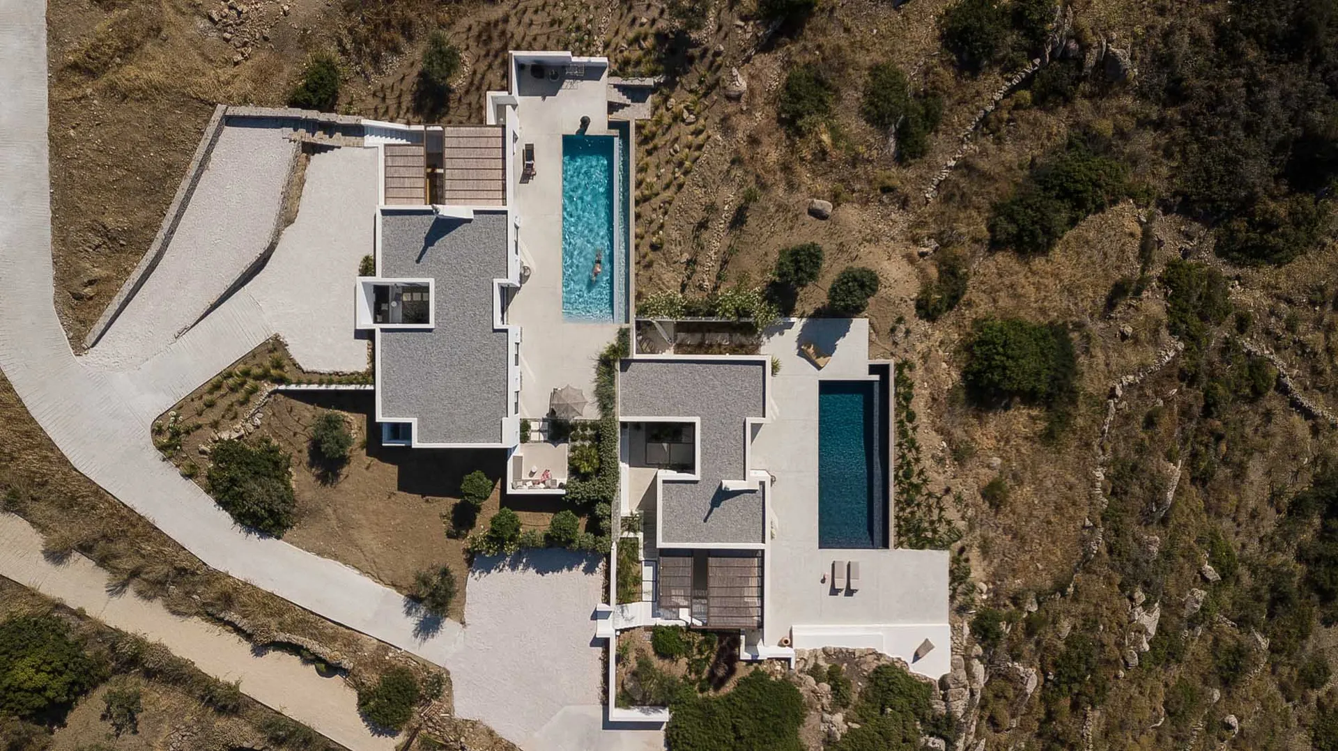 Aerial view of a modern residential home featuring concrete and glass materials.
