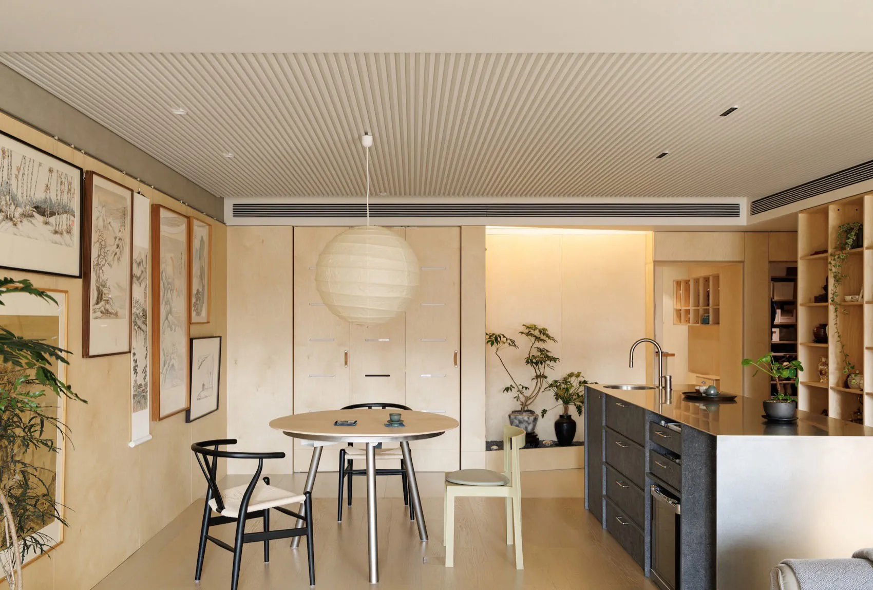 A modern, minimalist residential kitchen featuring light-colored wood cabinets and flooring.