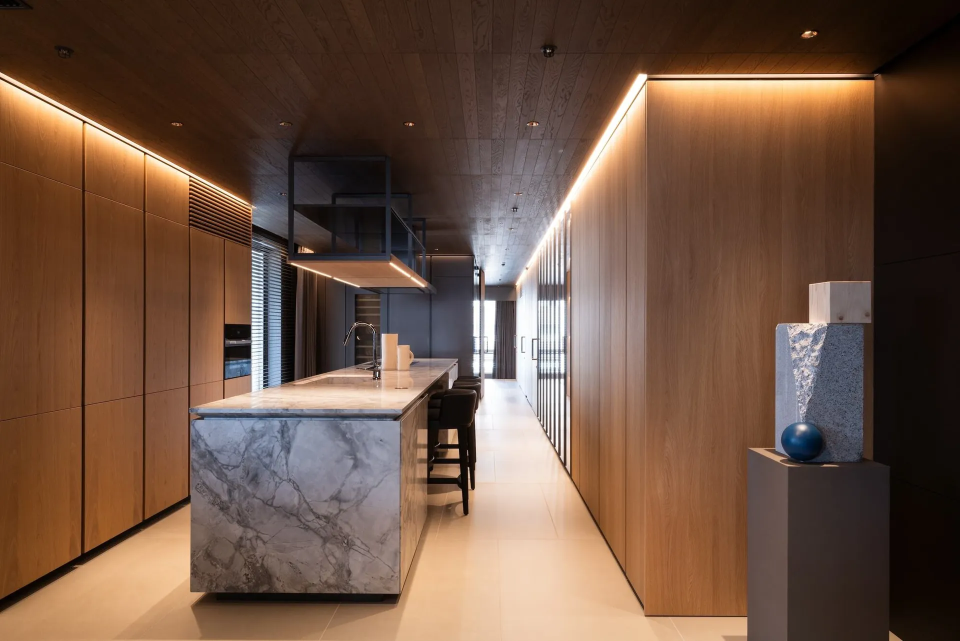 Modern, minimalist kitchen with wooden cabinets and marble countertops.